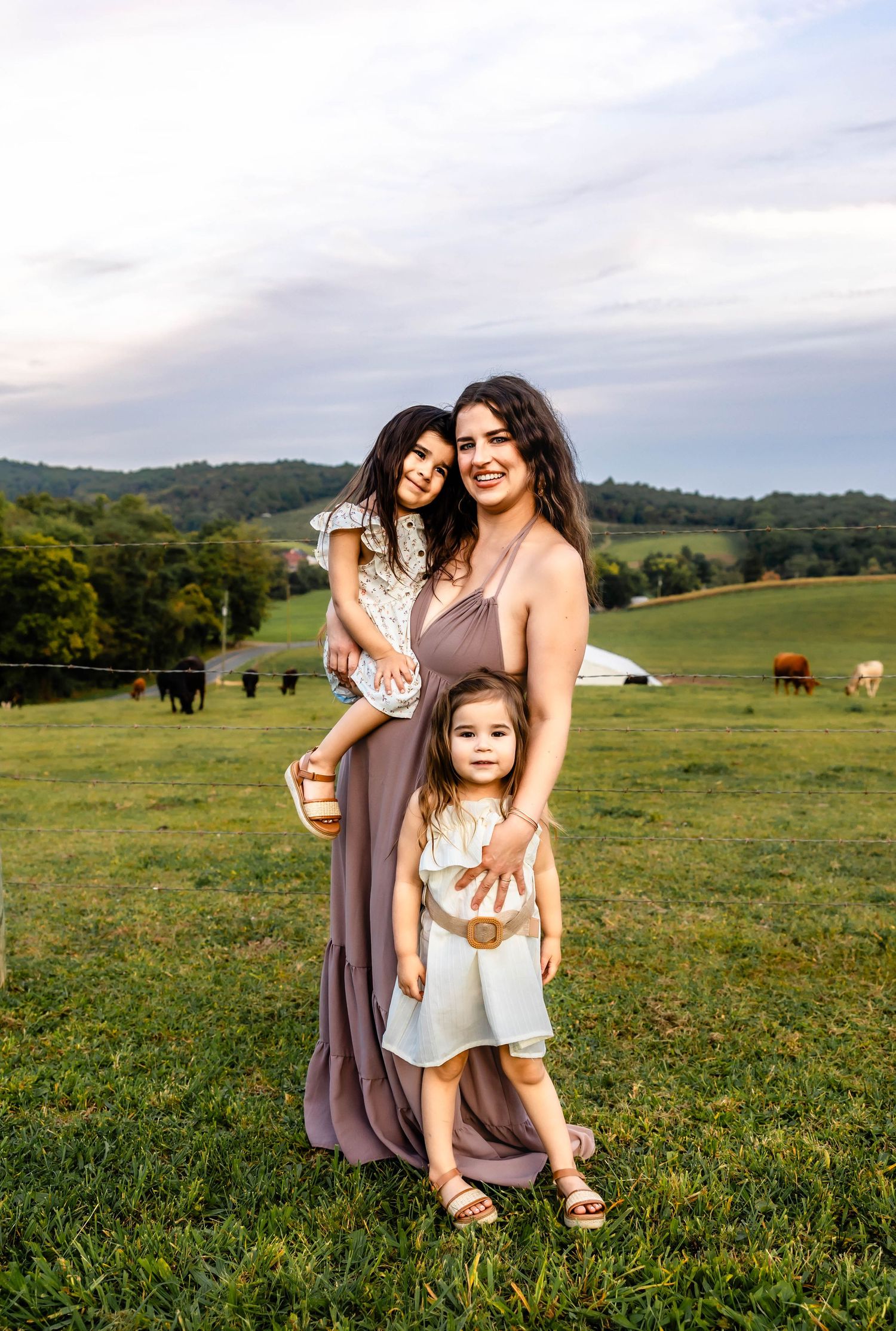 A family portrait set against a scenic backdrop of rolling hills and grazing cattle.