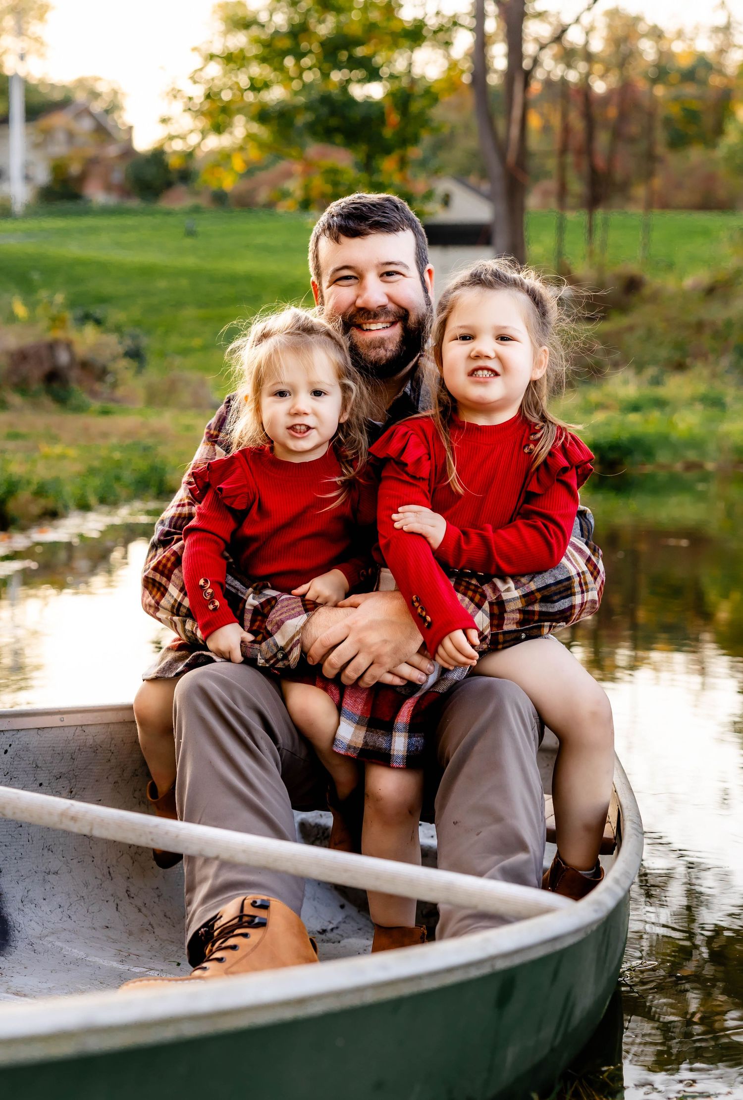 Three people in red outfits share happy moment together in canoe during fall.