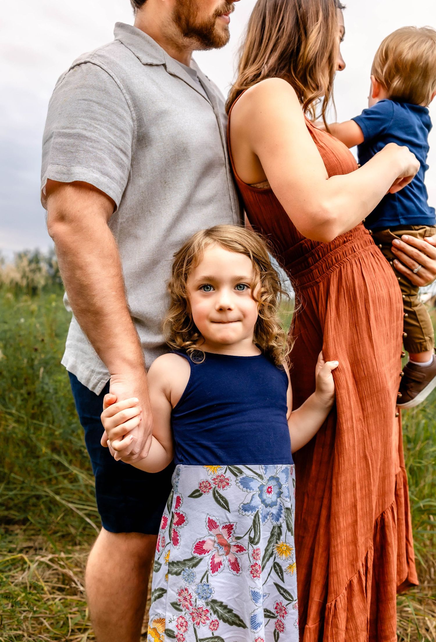 Close-up portrait of a family in coordinated outfits standing in a summer meadow.