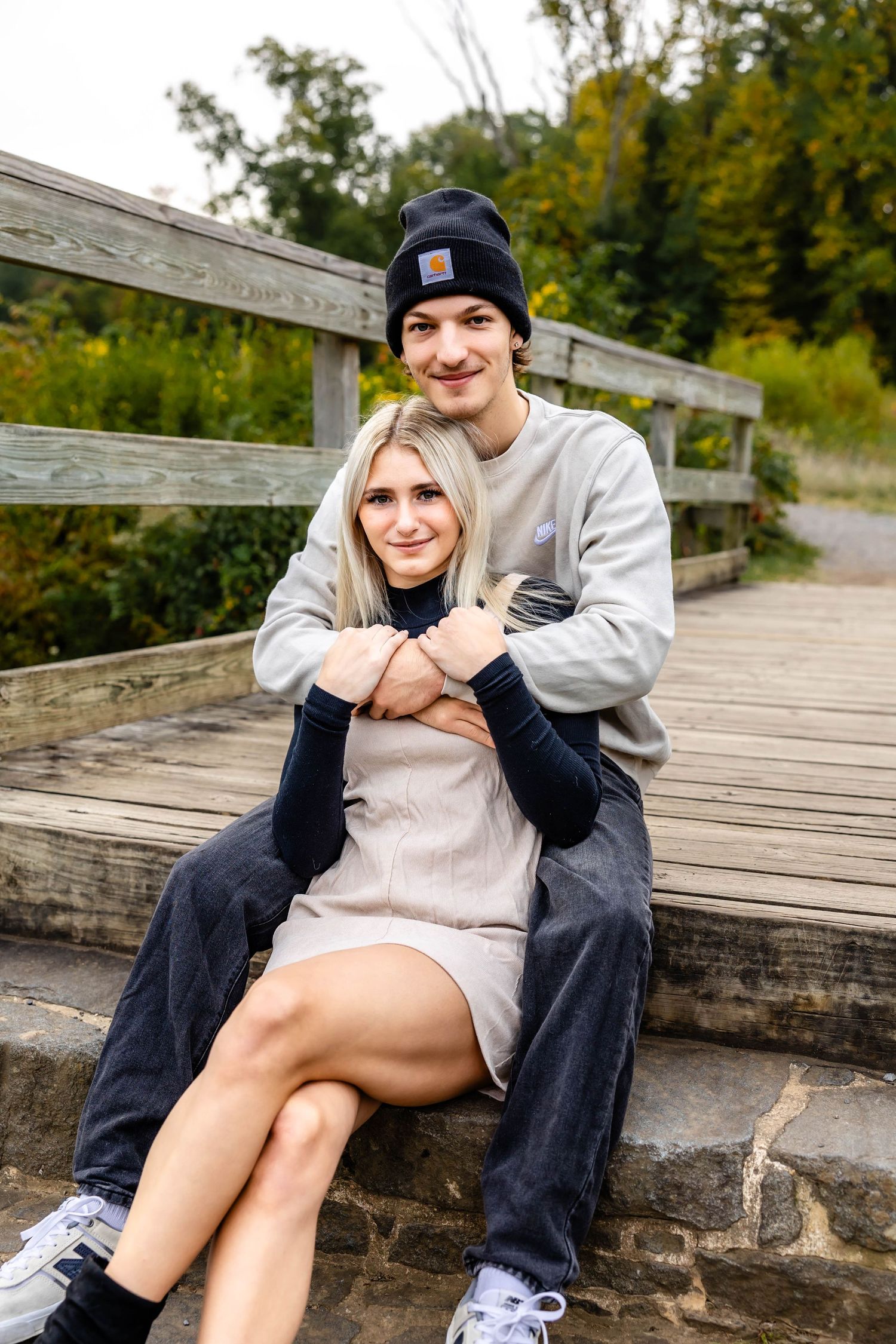 Couple in casual winter wear shares intimate moment on wooden boardwalk steps.