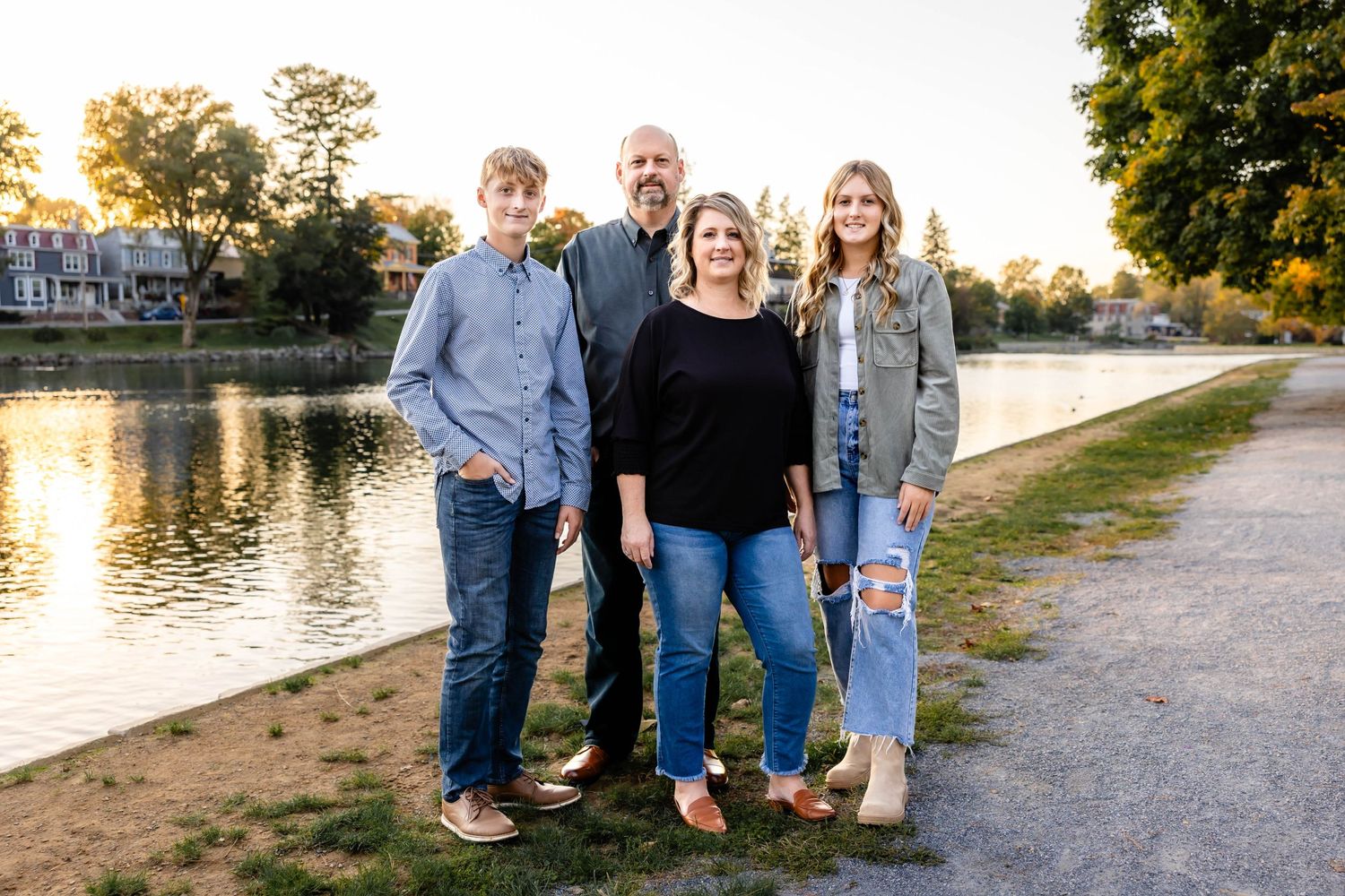 A family group poses together on a waterfront path during golden hour.