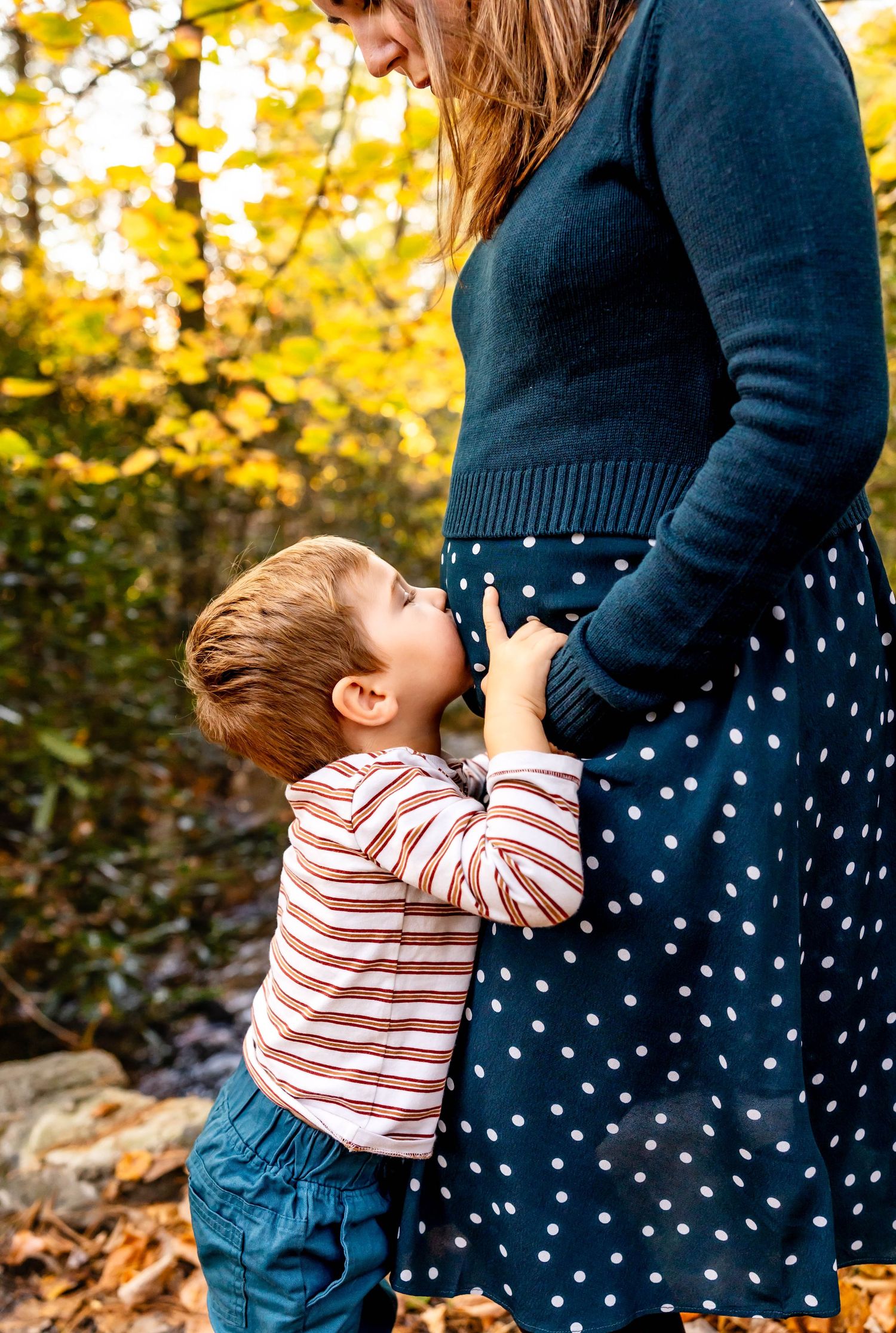 Tender moment between parent and child against vibrant fall foliage.