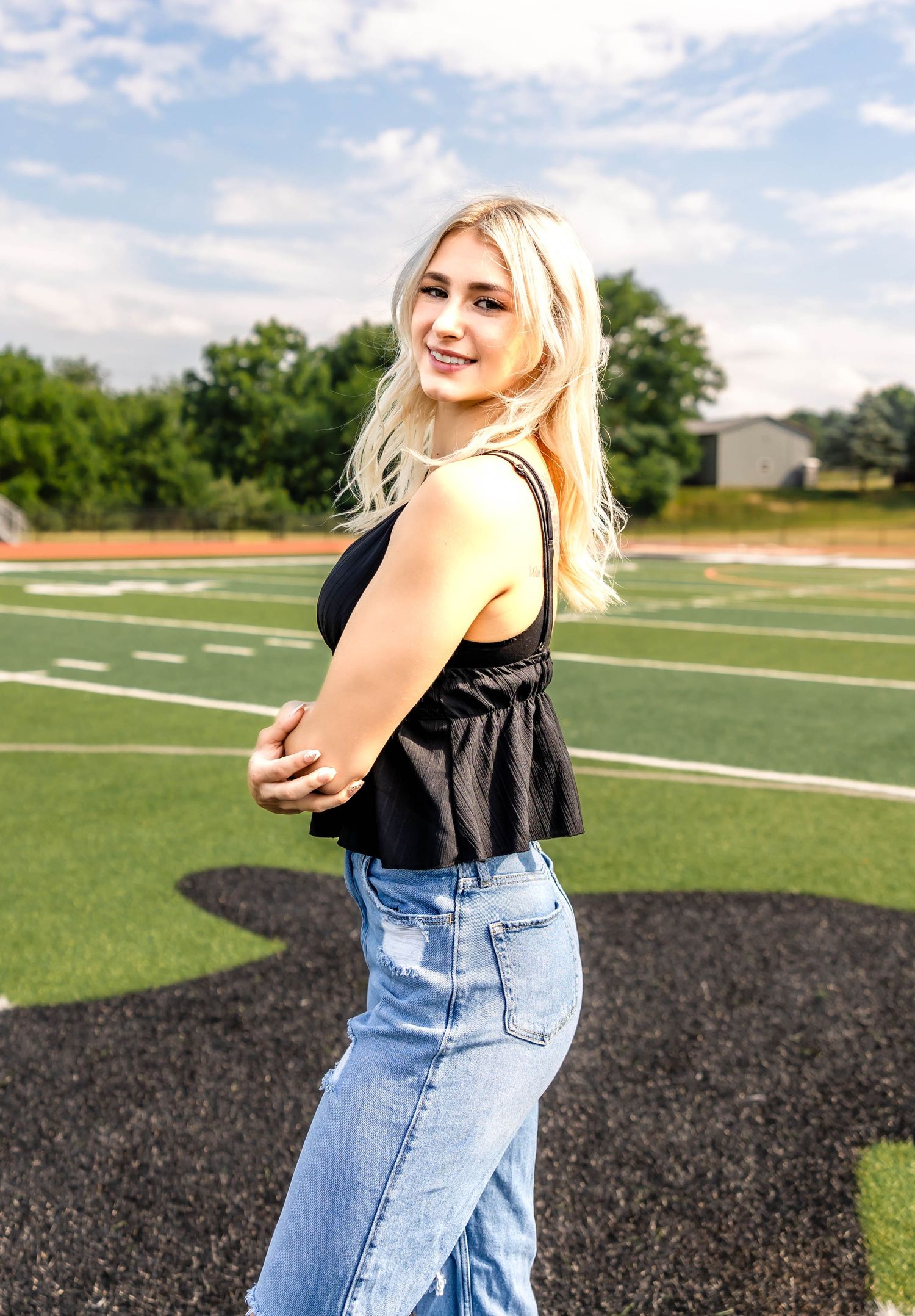 Candid side profile shot on football field wearing black top and denim.