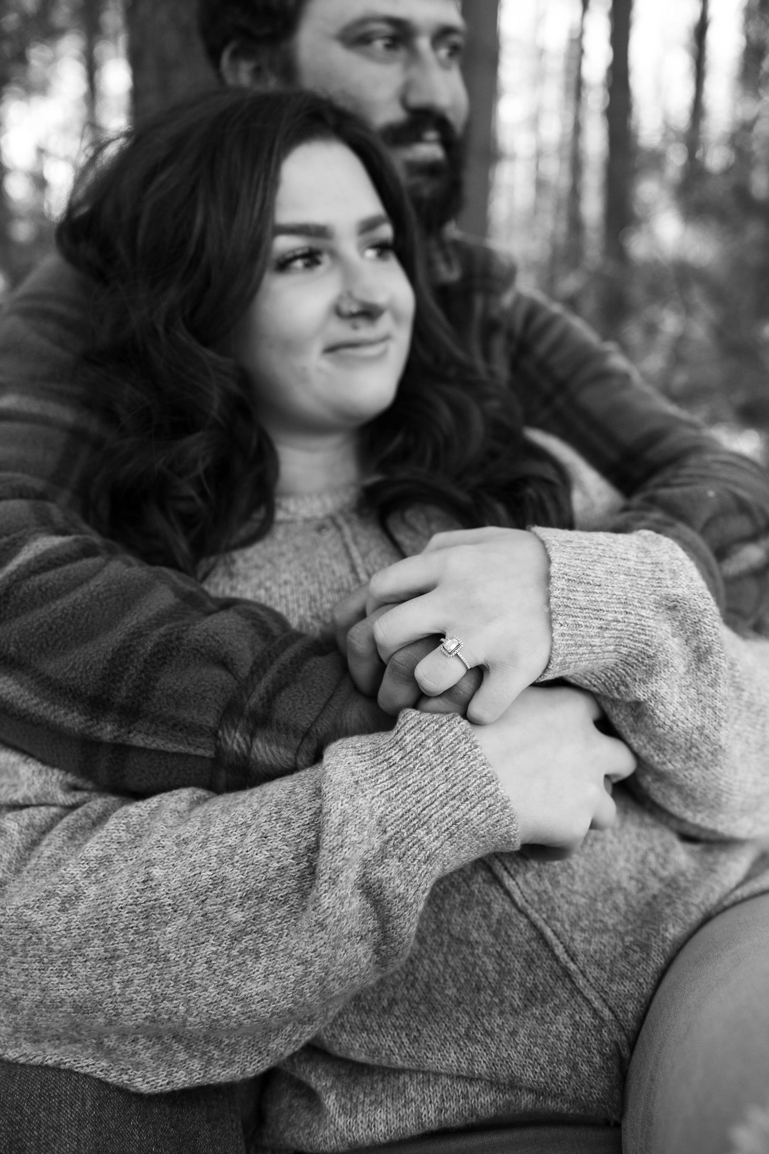 A black and white portrait of a couple sharing an intimate embrace in the woods.
