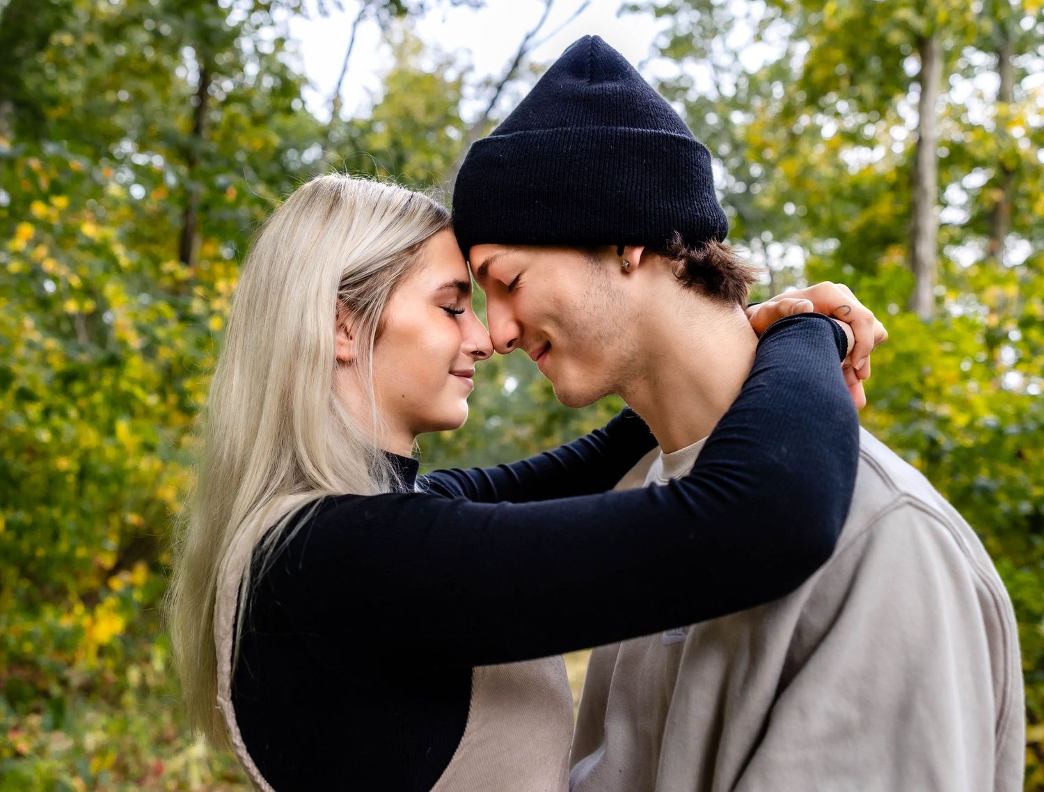 Intimate portrait of couple embracing on fall forest path.