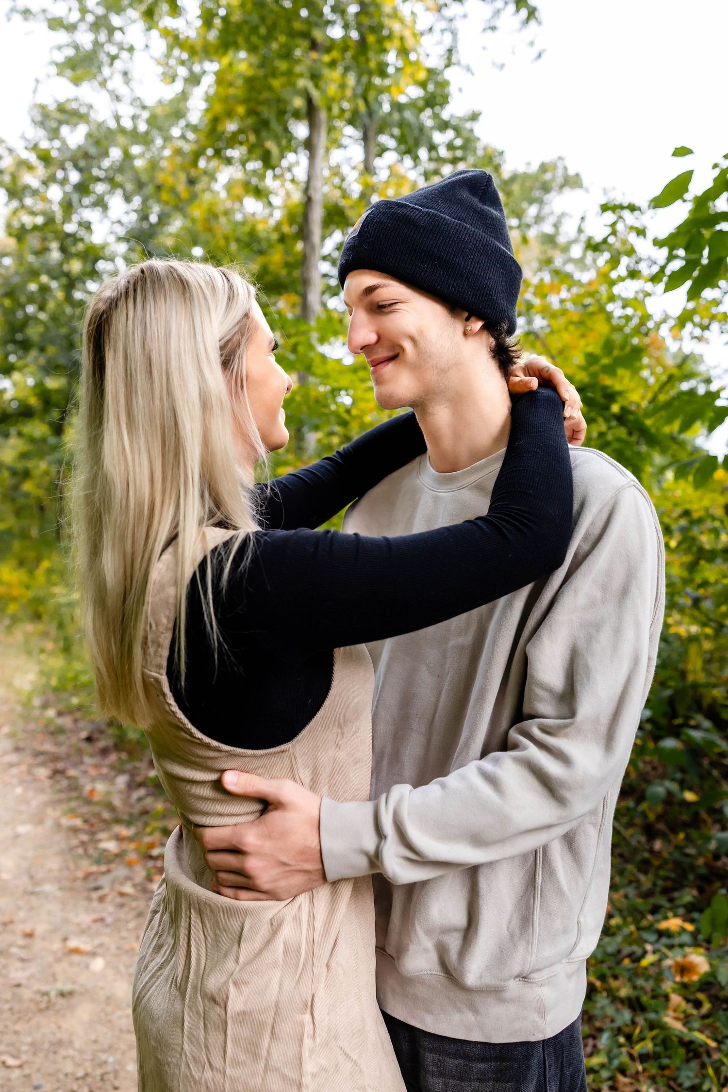 A couple shares an intimate moment on a forest trail during autumn.