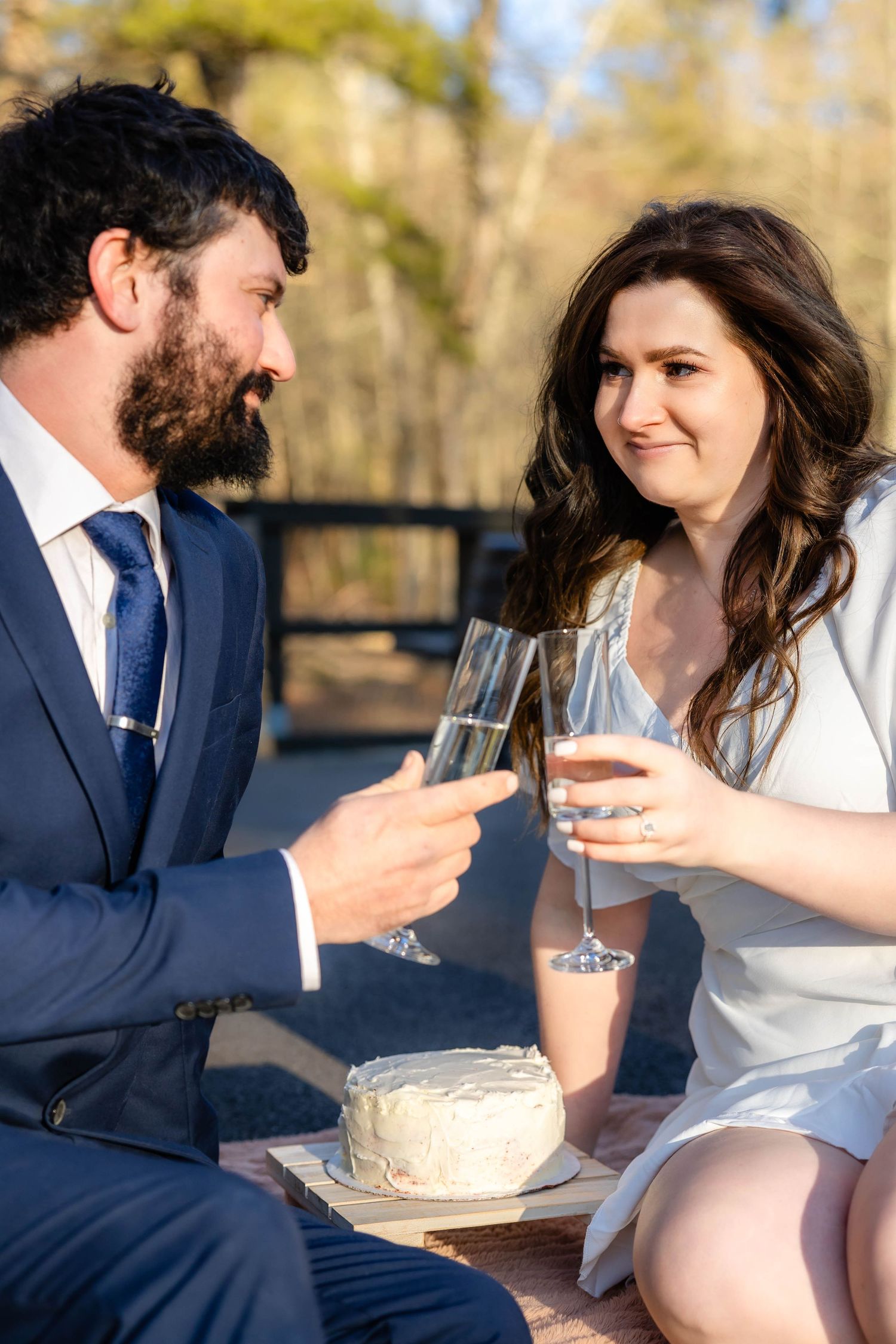 A couple toasts with champagne glasses during an outdoor celebration.