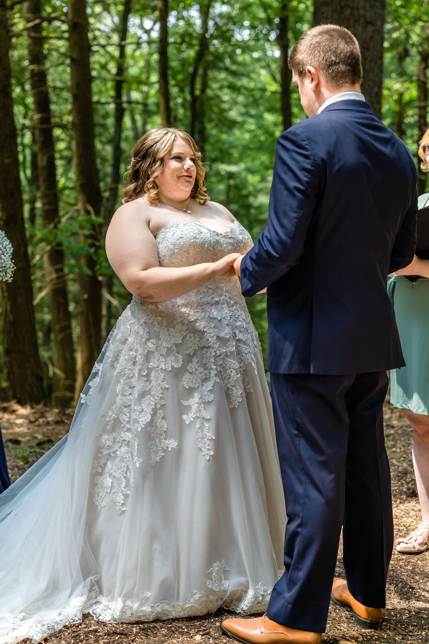 Wedding ceremony taking place on natural forest path with lace detail dress.