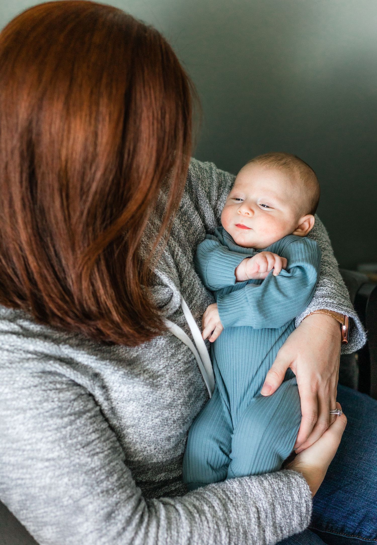 Intimate parenting moment in a cozy gray and blue setting.