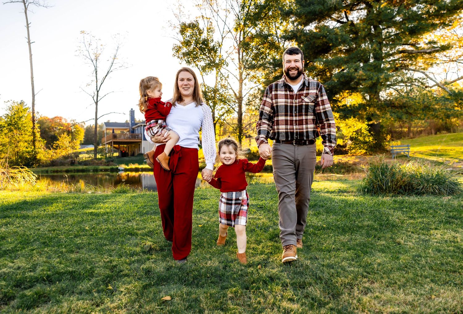 Family walking together in coordinated outfits during golden hour in grassy field.