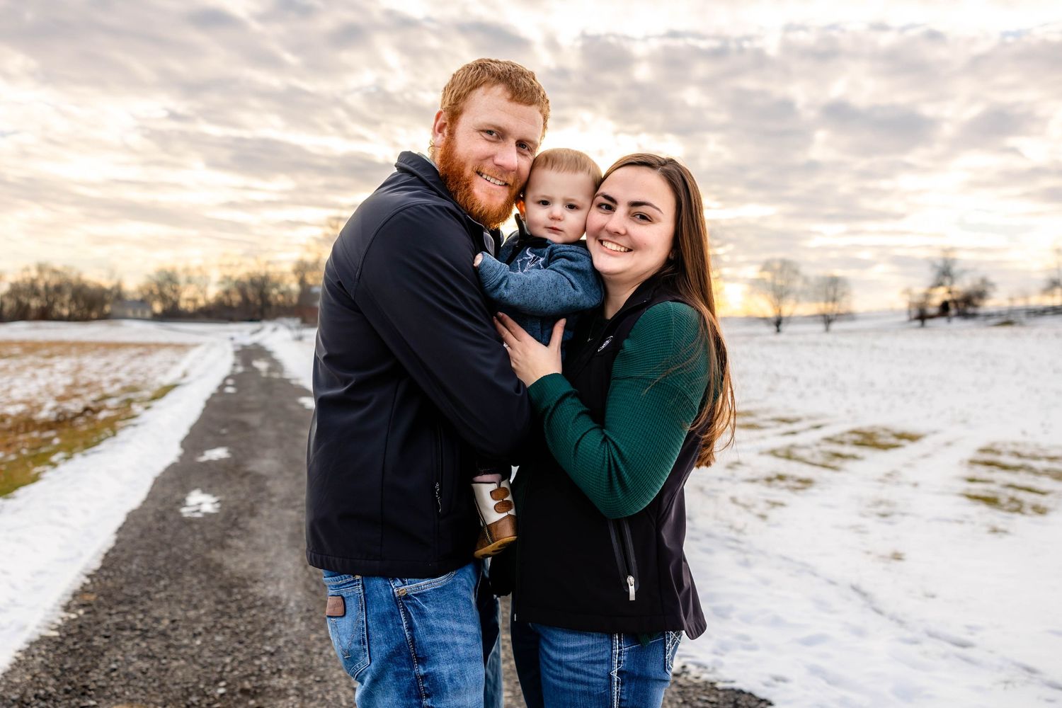 Loving family moment captured against winter sunset landscape.