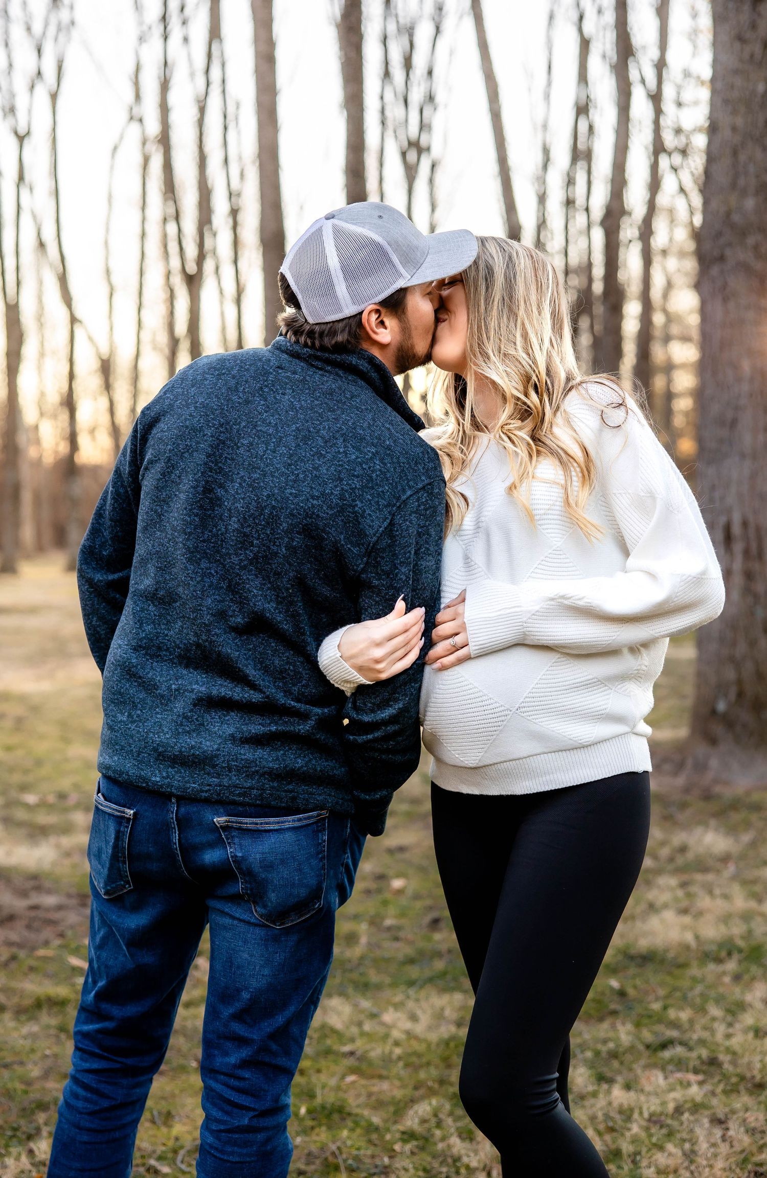 Romantic moment between couple in matching casual wear against a backdrop of winter trees.