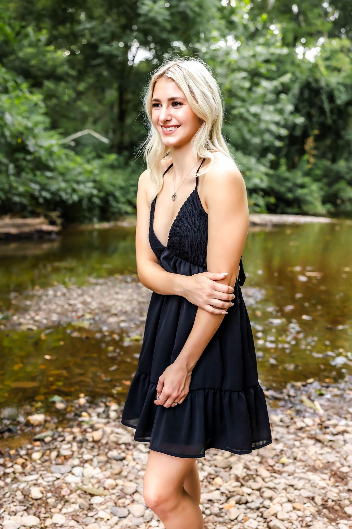 A summer portrait featuring a black dress against a natural creek backdrop.