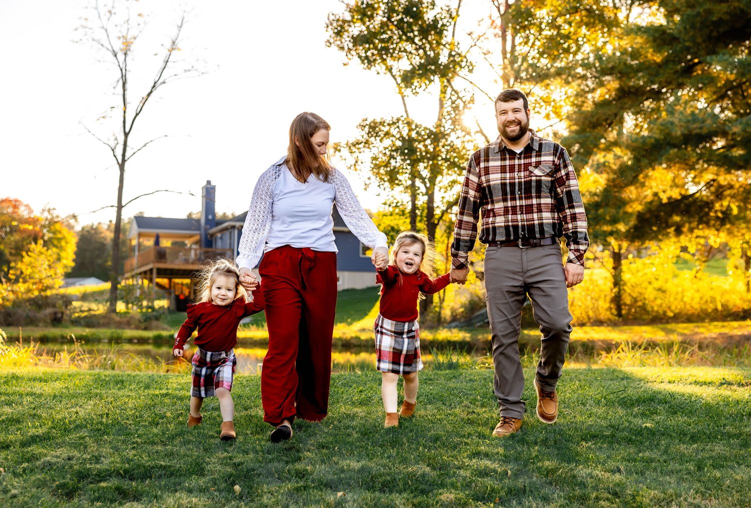 Family strolling together through field during sunset in coordinated casual outfits.