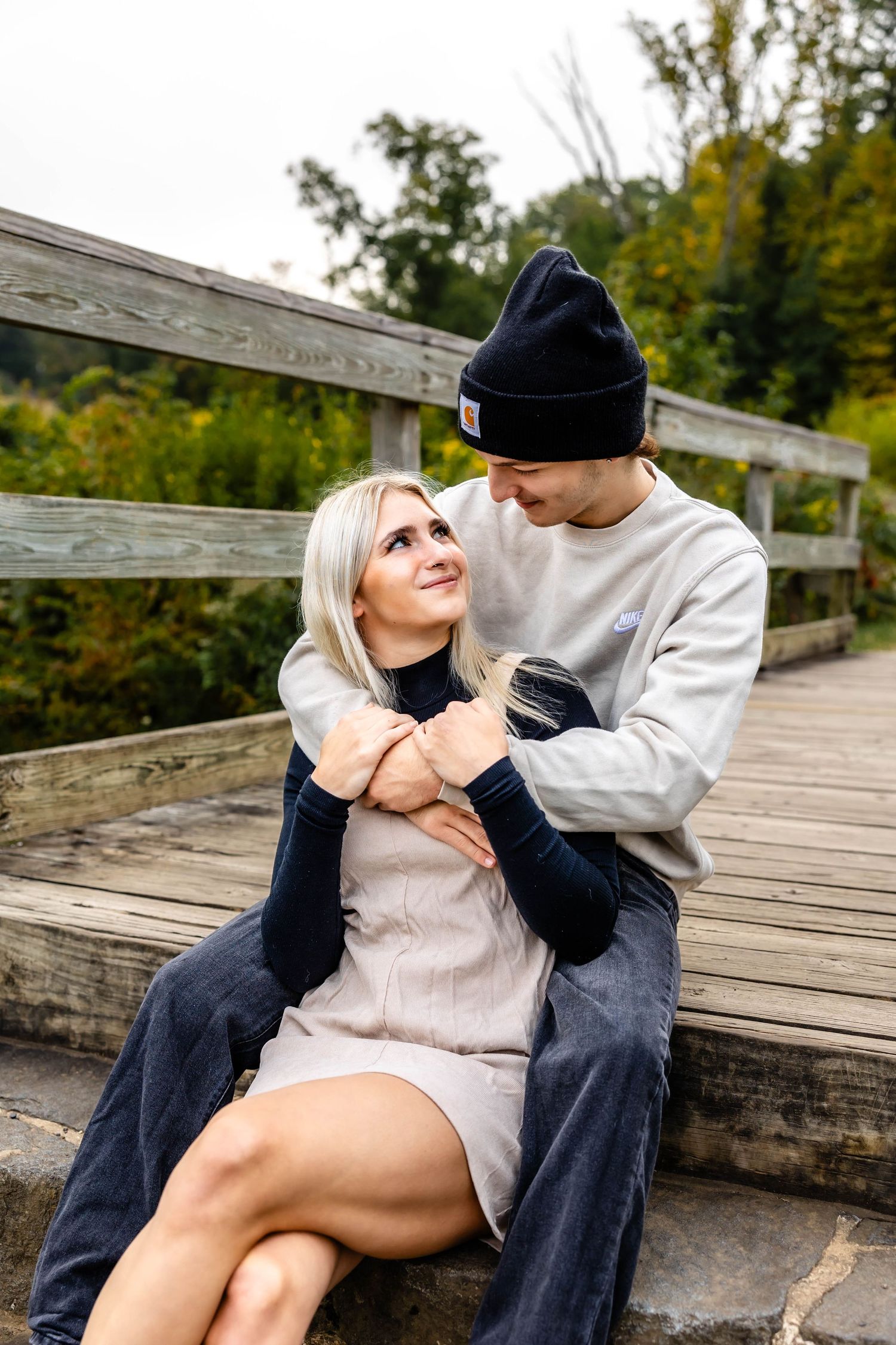 A couple shares a tender moment while sitting on wooden steps outdoors.