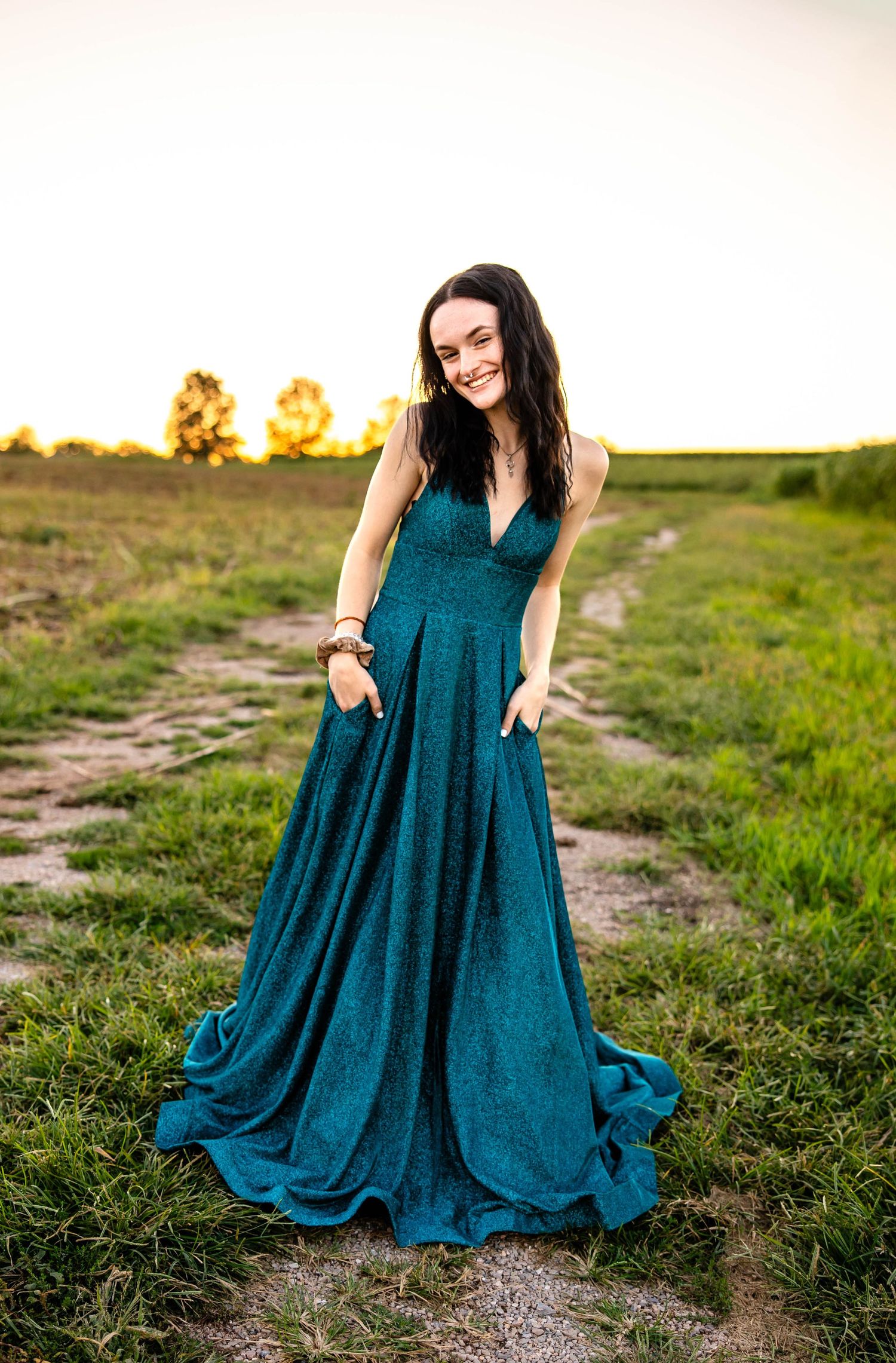 Dramatic teal evening gown photo at sunset on rural path.