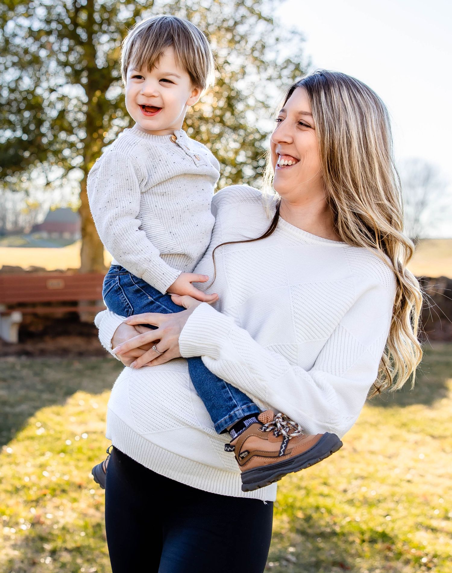 Joyful outdoor family moment with parent and toddler in coordinating white sweaters.