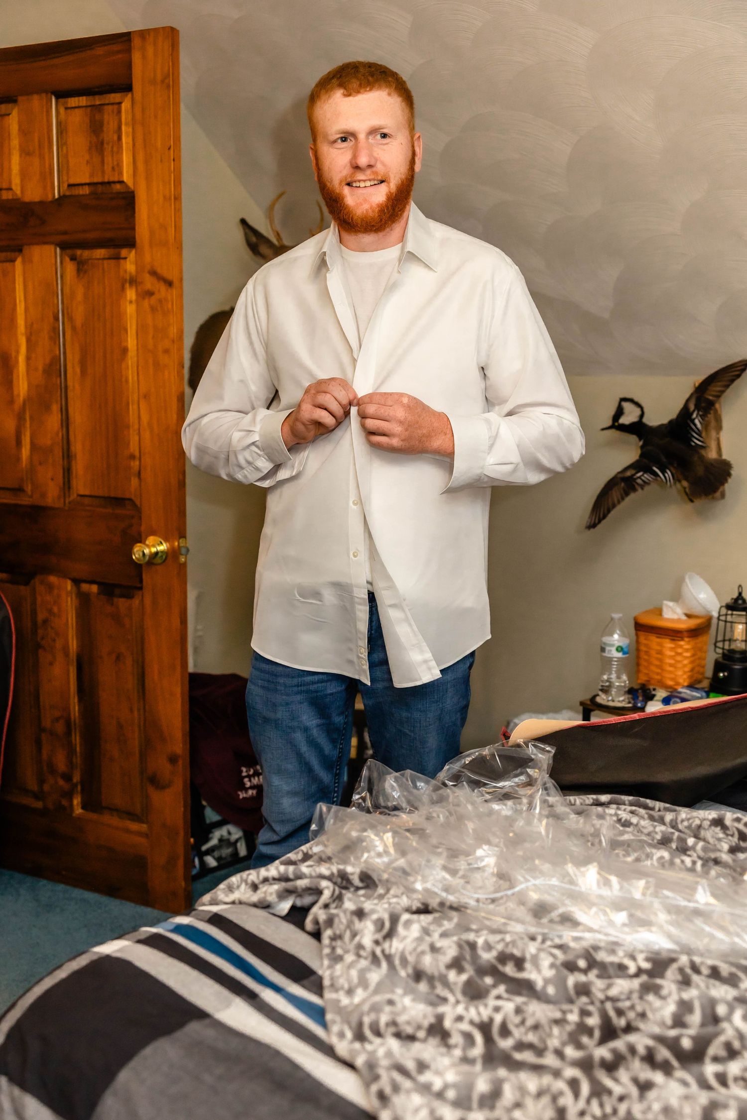 Individual preparing formal attire in bedroom with wooden door and decor.
