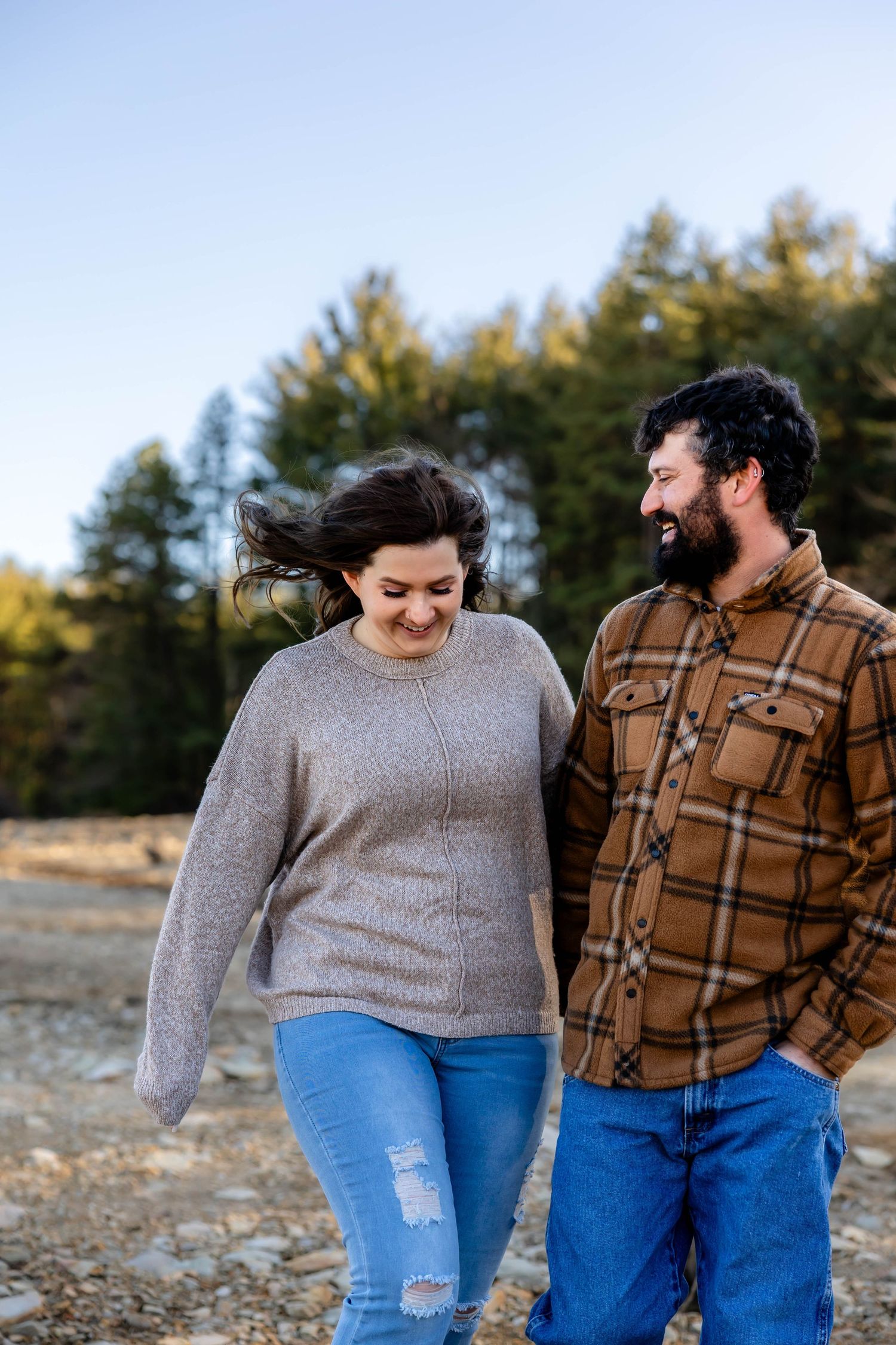 A joyful couple shares a laugh while walking together on a sunny day.