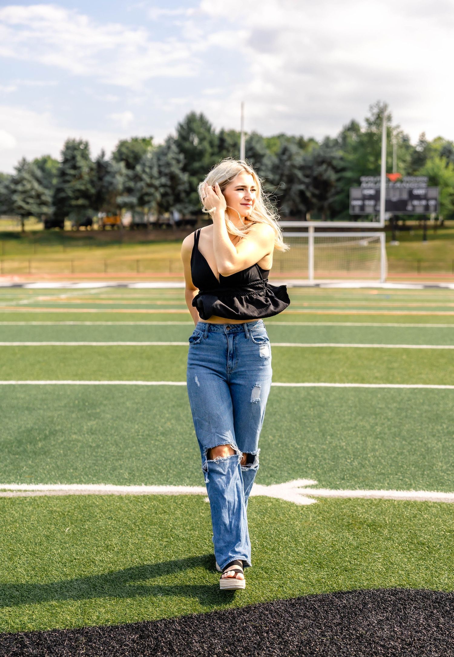 Full body fashion shot on football field wearing casual summer outfit.