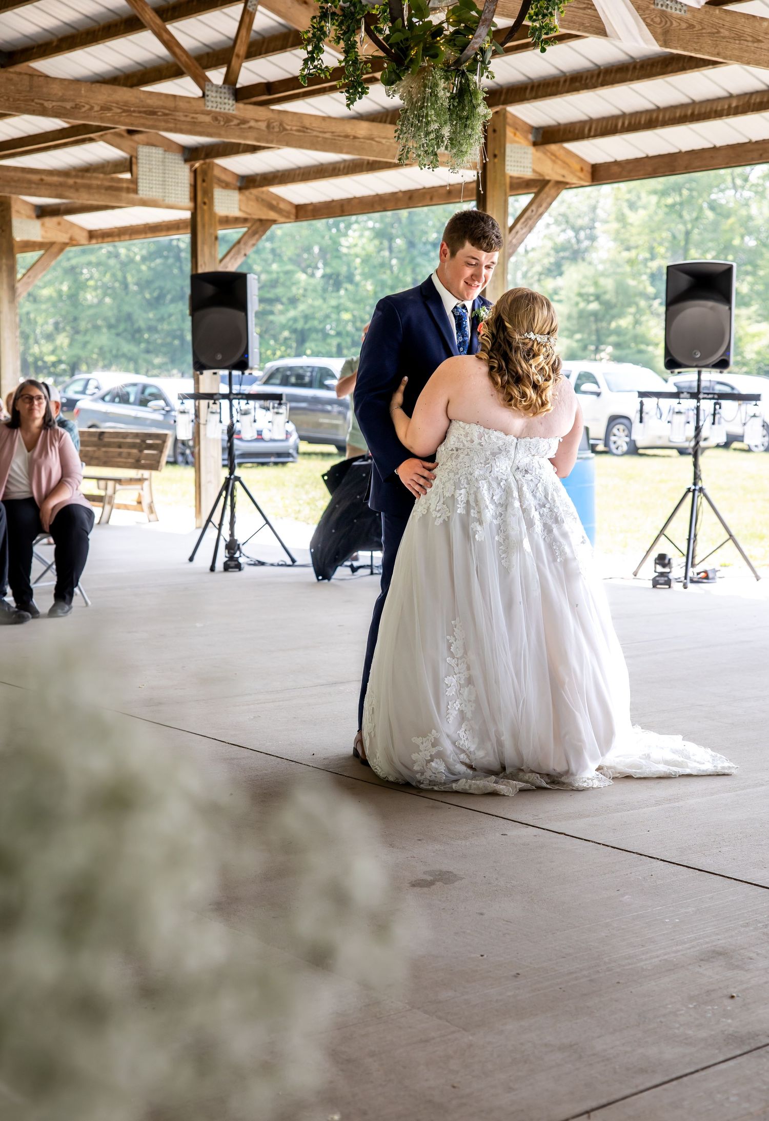 A couple shares their first dance under a covered outdoor wedding venue.