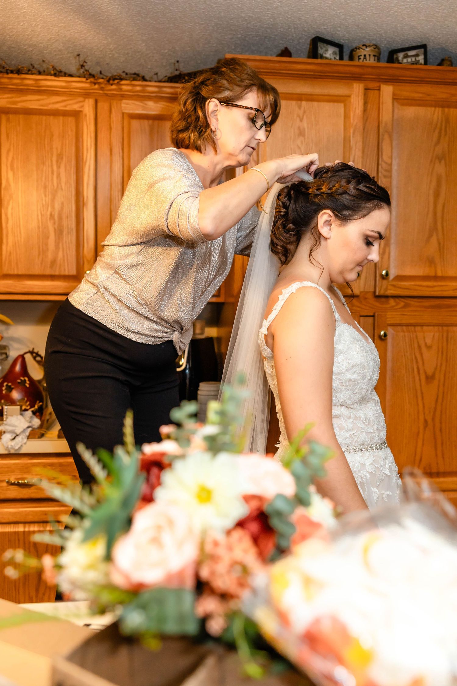 A person helps style the bride's hair and veil before the wedding ceremony.