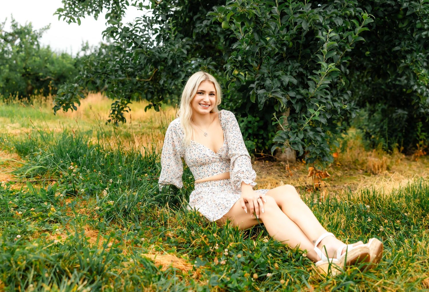 Relaxed countryside fashion photo of a two-piece floral outfit in a summer orchard.