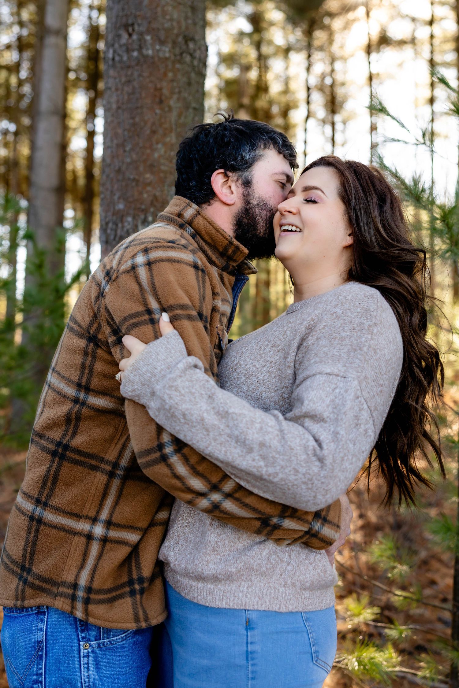 A loving couple shares a joyful moment together in a wooded setting during golden hour.
