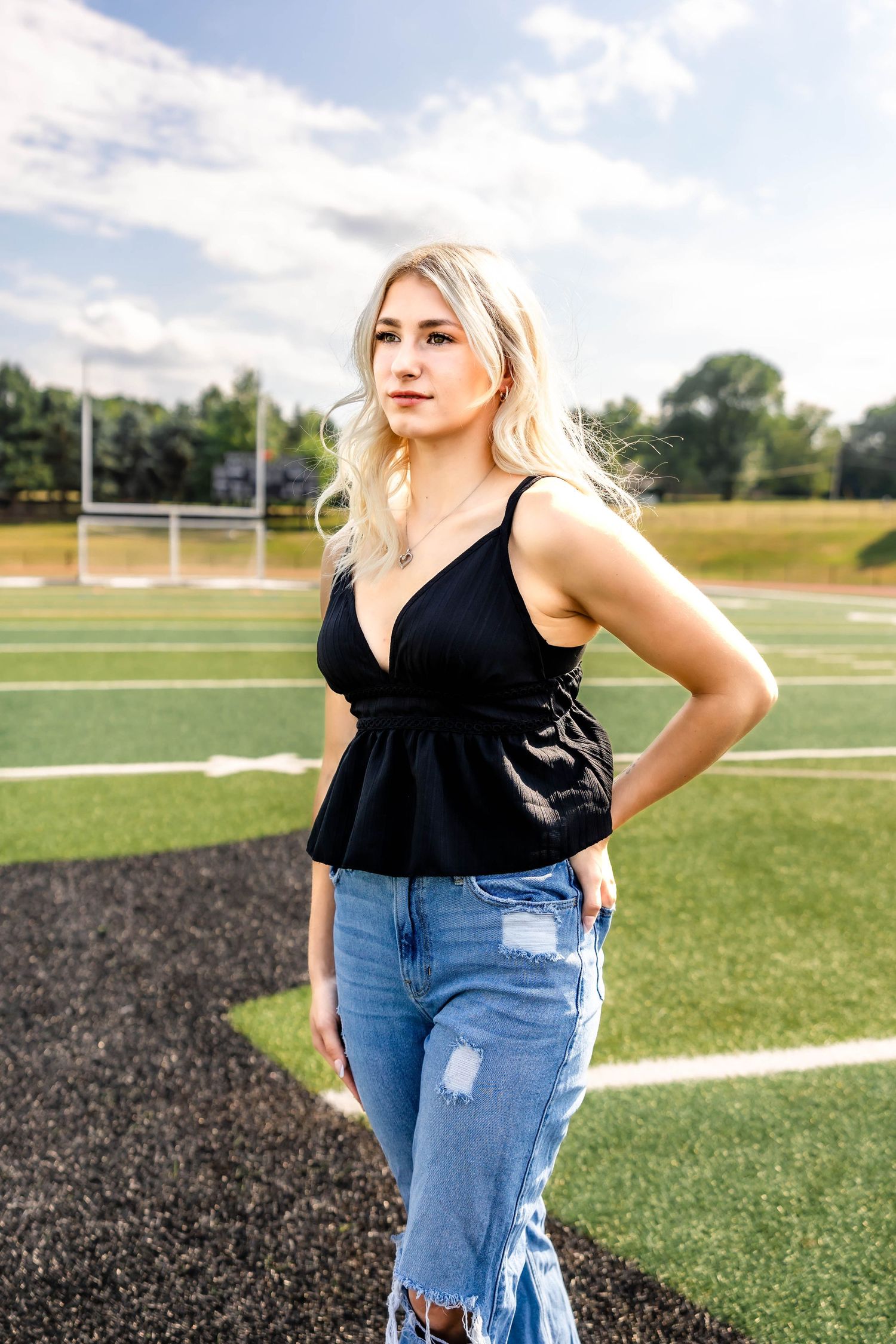 Fashion portrait on football field wearing black peplum top and ripped jeans.
