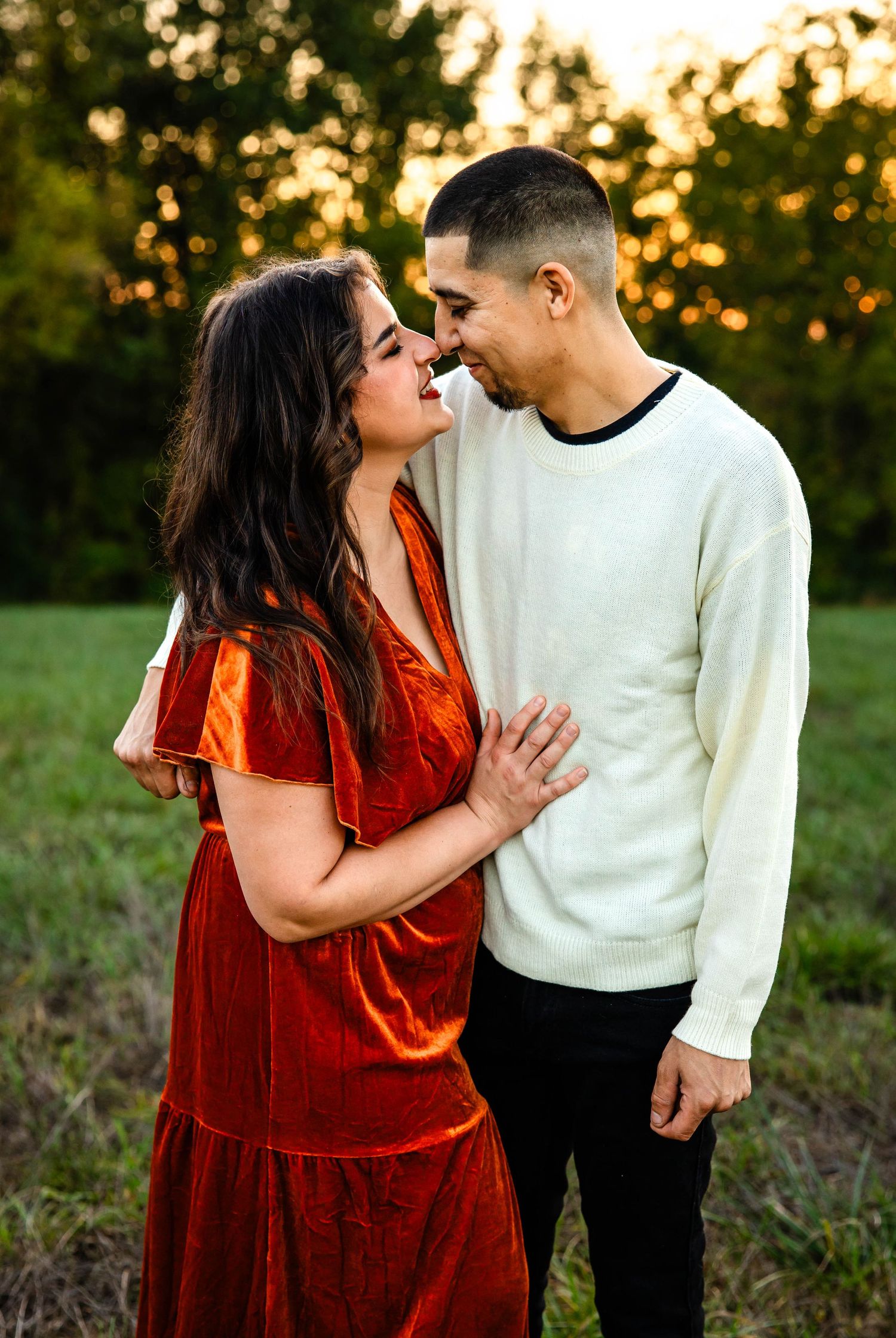 Romantic sunset portrait of couple in field with glowing evening light.
