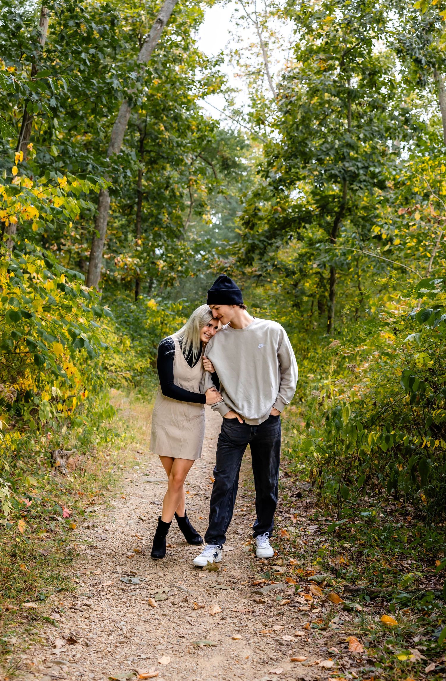 Couple in coordinated outfits sharing intimate moment on autumn hiking trail.