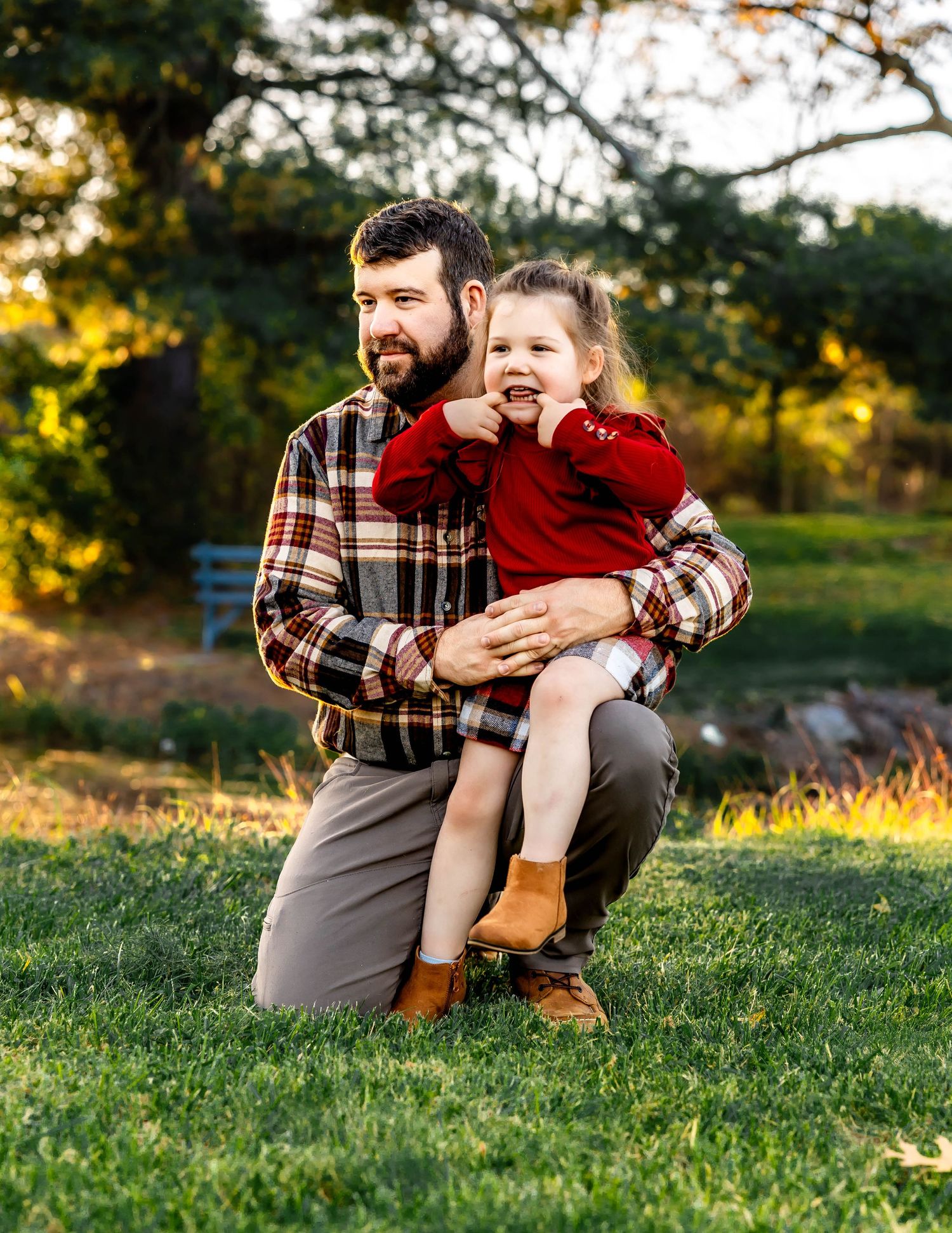 Adult and child in coordinating plaid and red outfits share a happy moment outdoors during autumn.