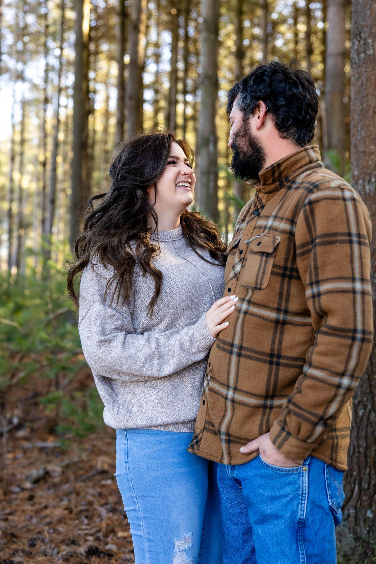 Couple sharing a tender moment in a sun-lit forest setting.