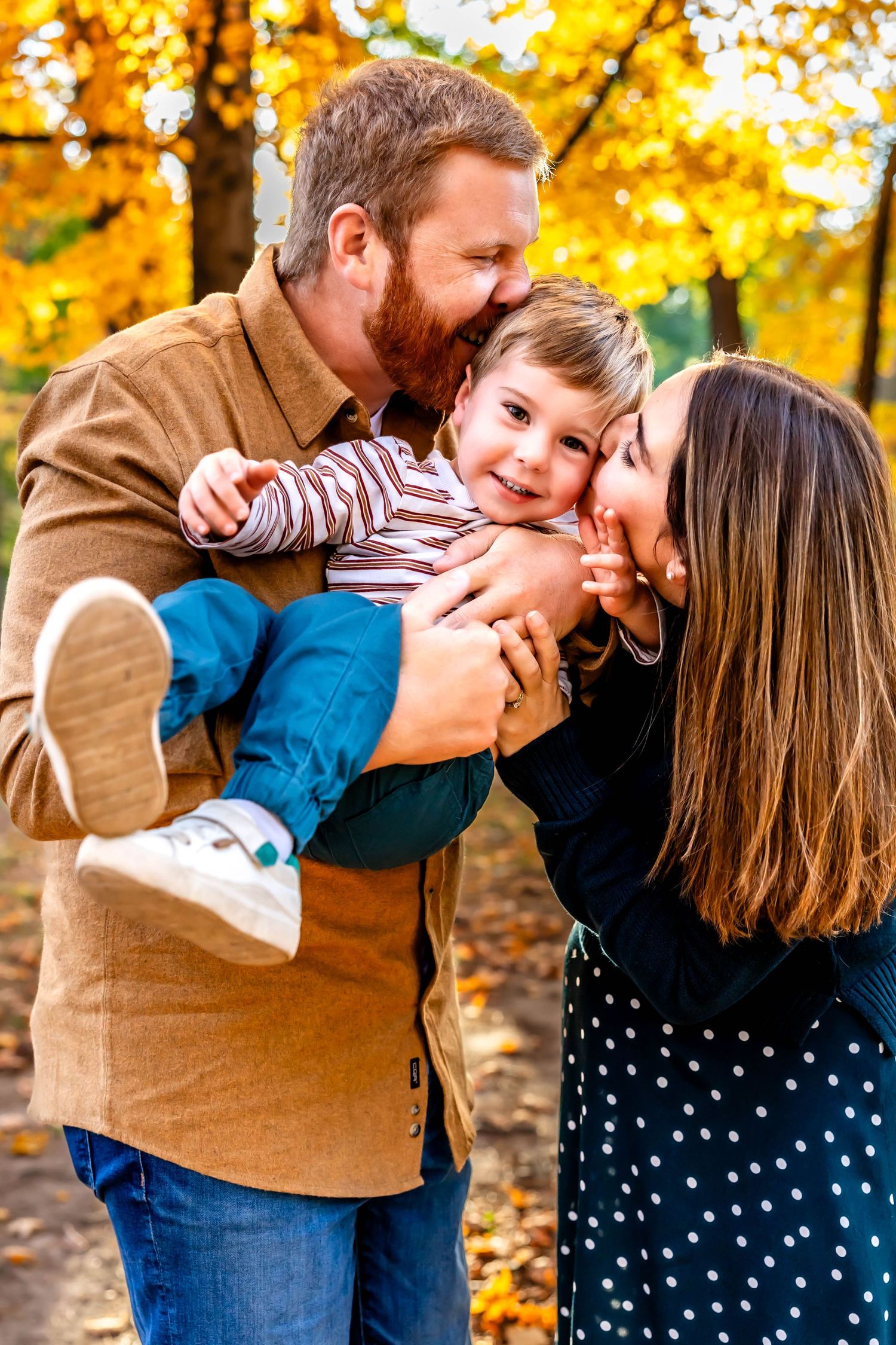 Family of three sharing joyful moment together among autumn leaves.