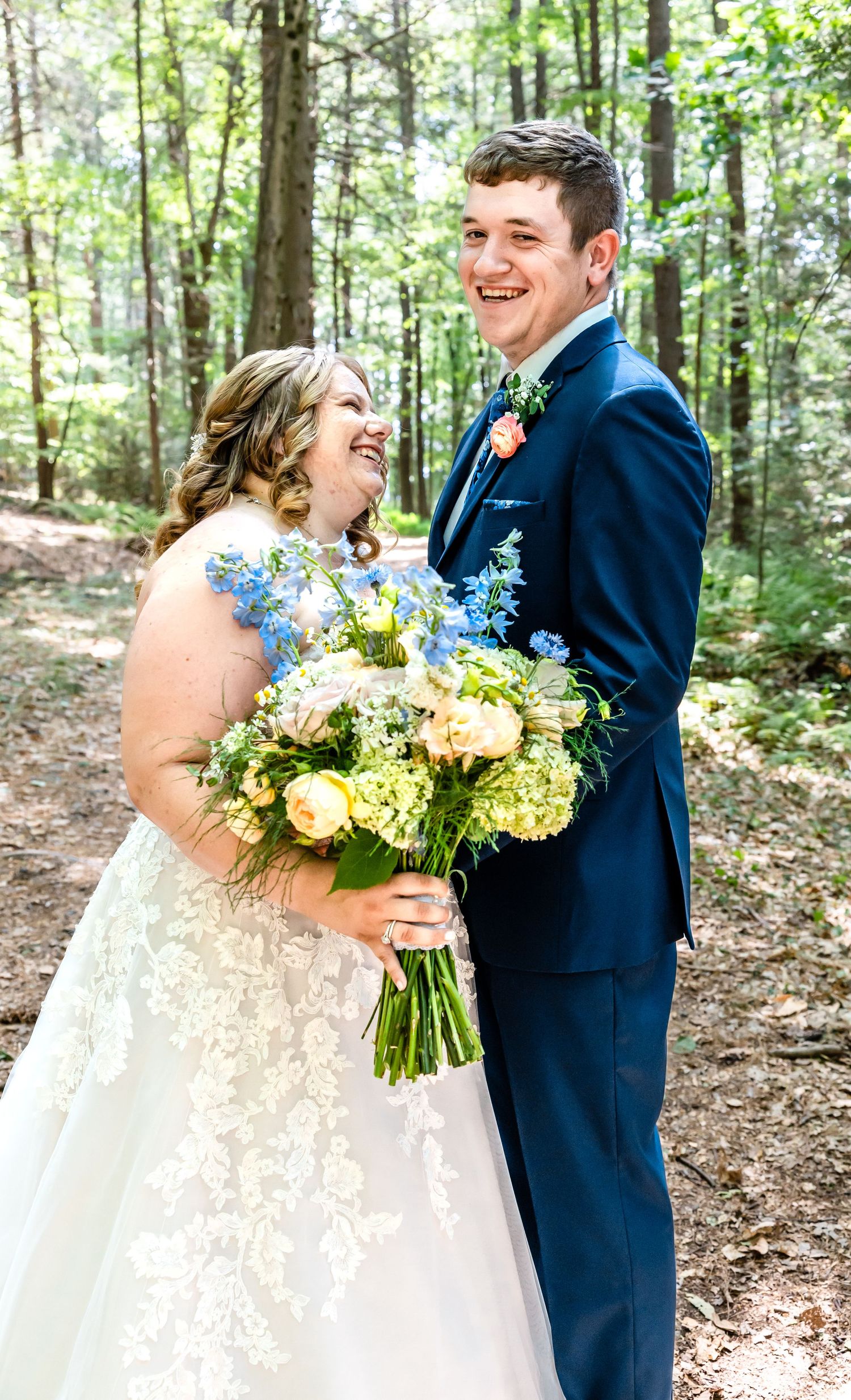 Candid moment of couple laughing together during forest wedding photoshoot.