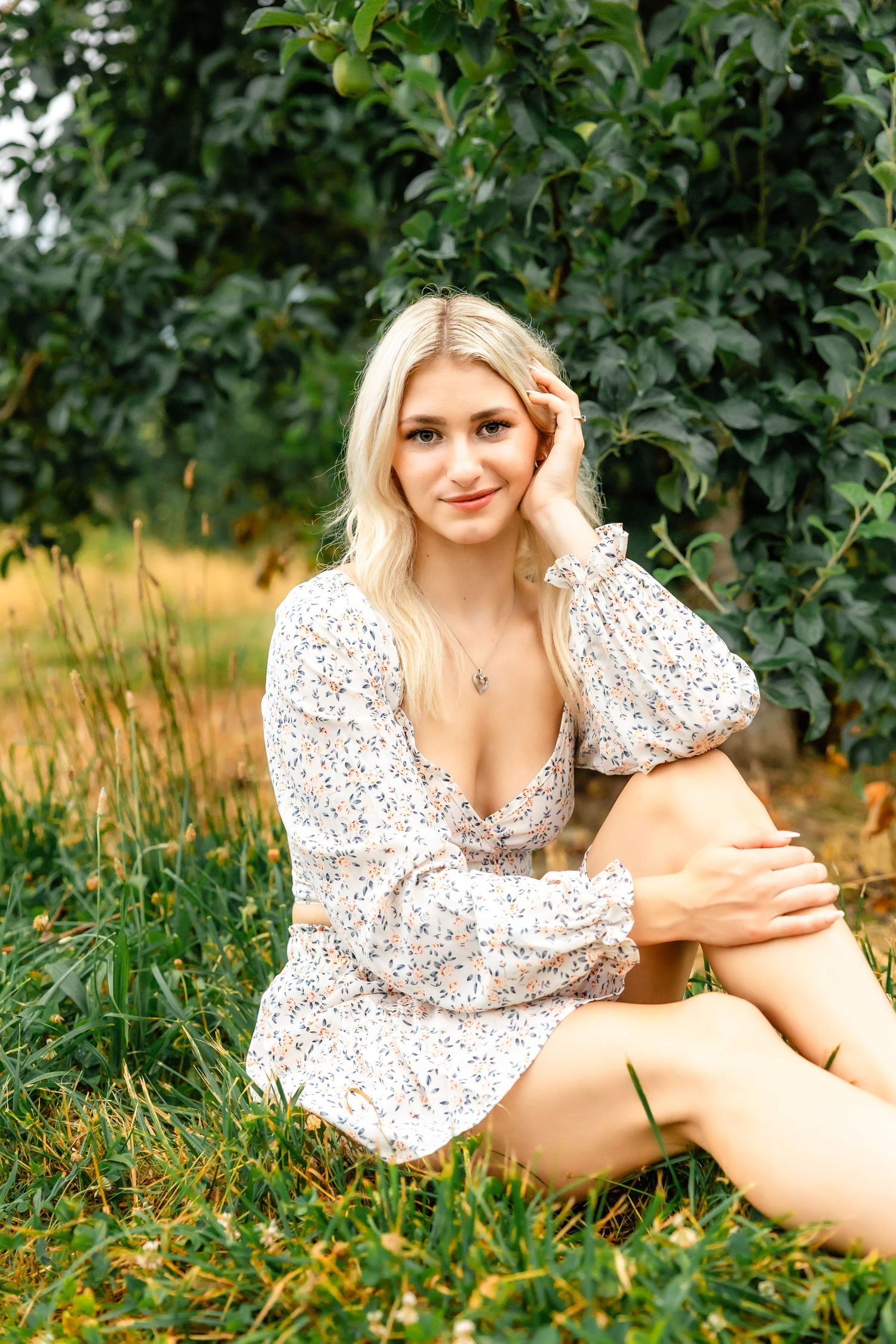 Summer portrait in a white floral dress against green foliage background.