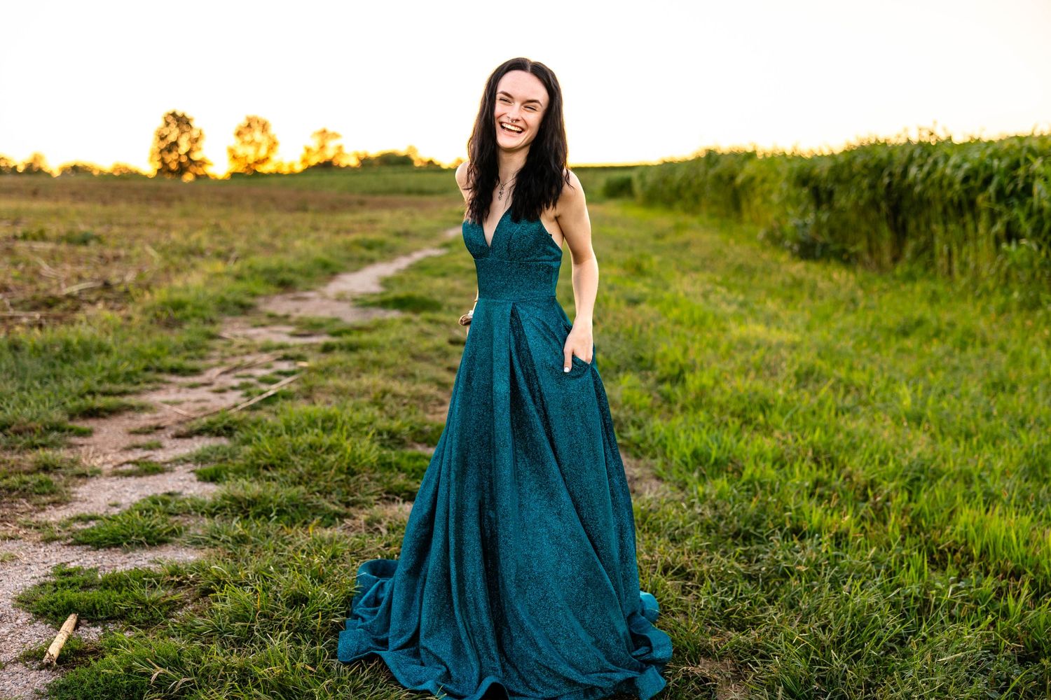 Elegant teal ballgown photoshoot on rustic dirt path at sunset.