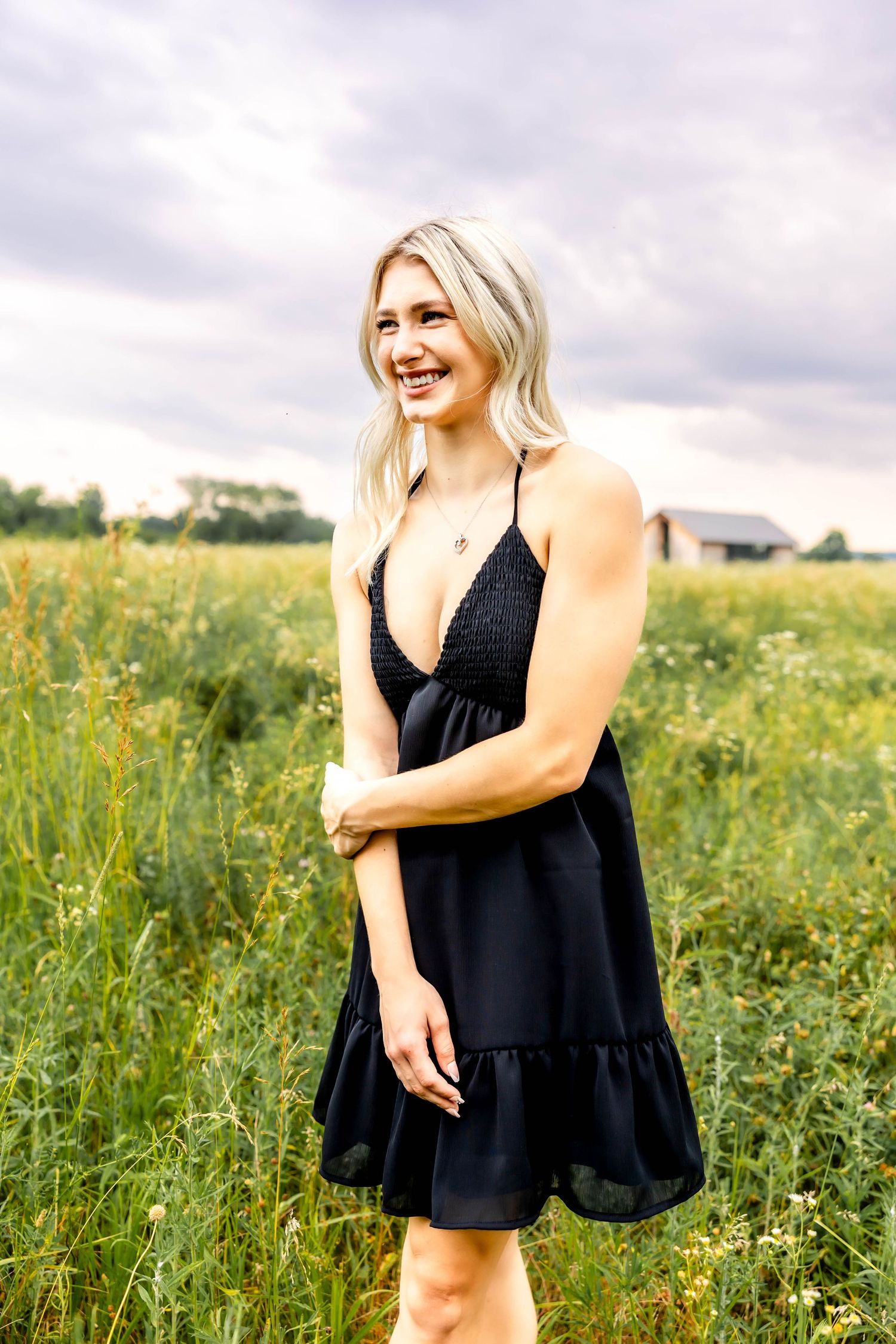 Casual black summer dress with V-neck styling photographed in a meadow of wildflowers.