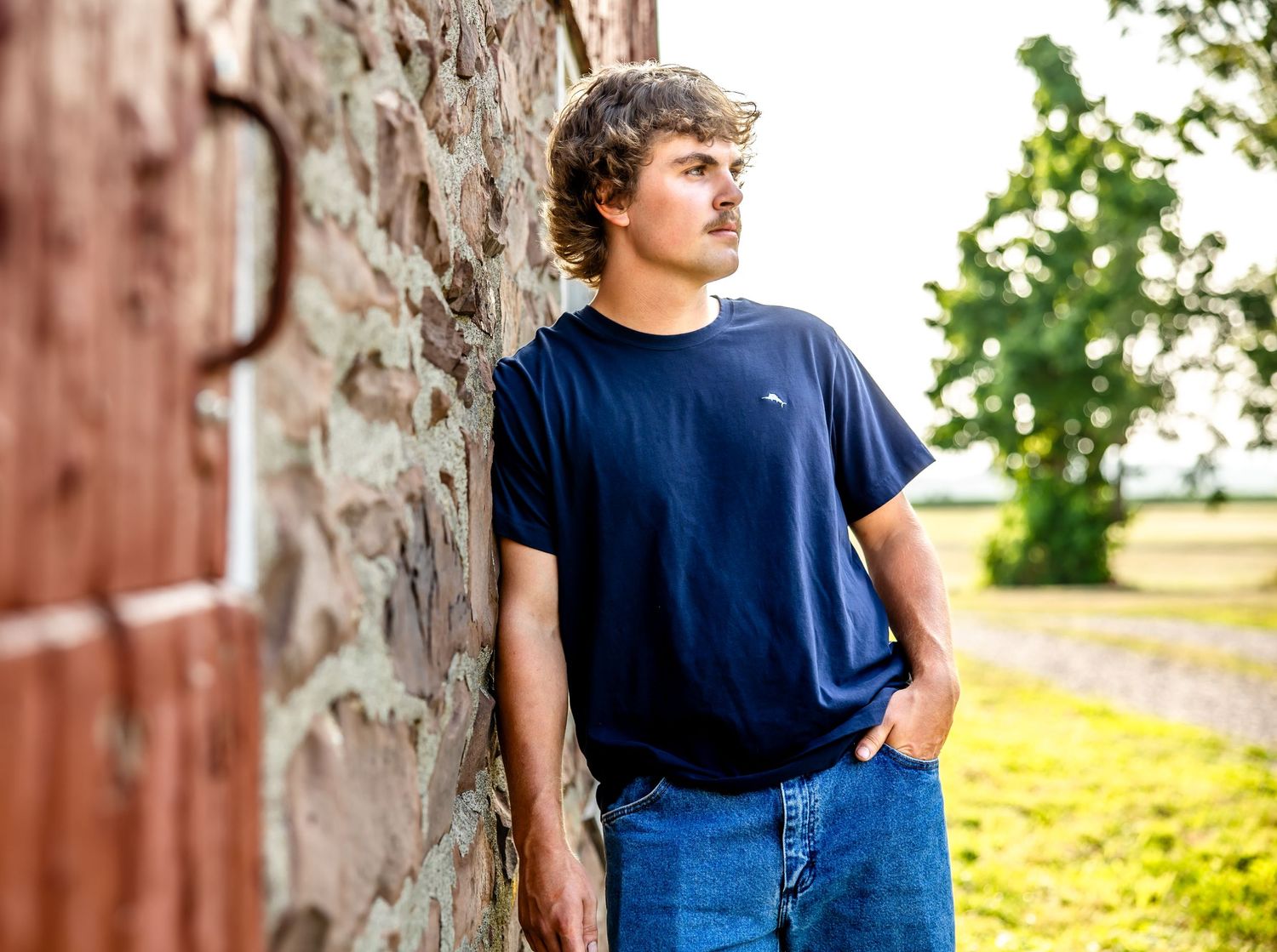 Casual outdoor portrait against weathered stone wall in simple blue attire.