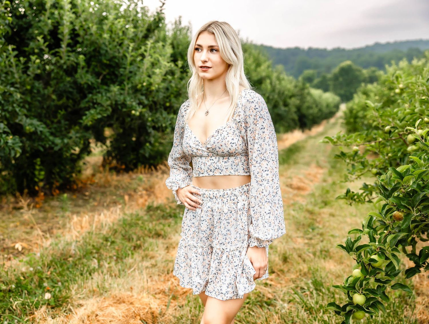 Romantic countryside portrait in a two-piece floral outfit with long bell sleeves.