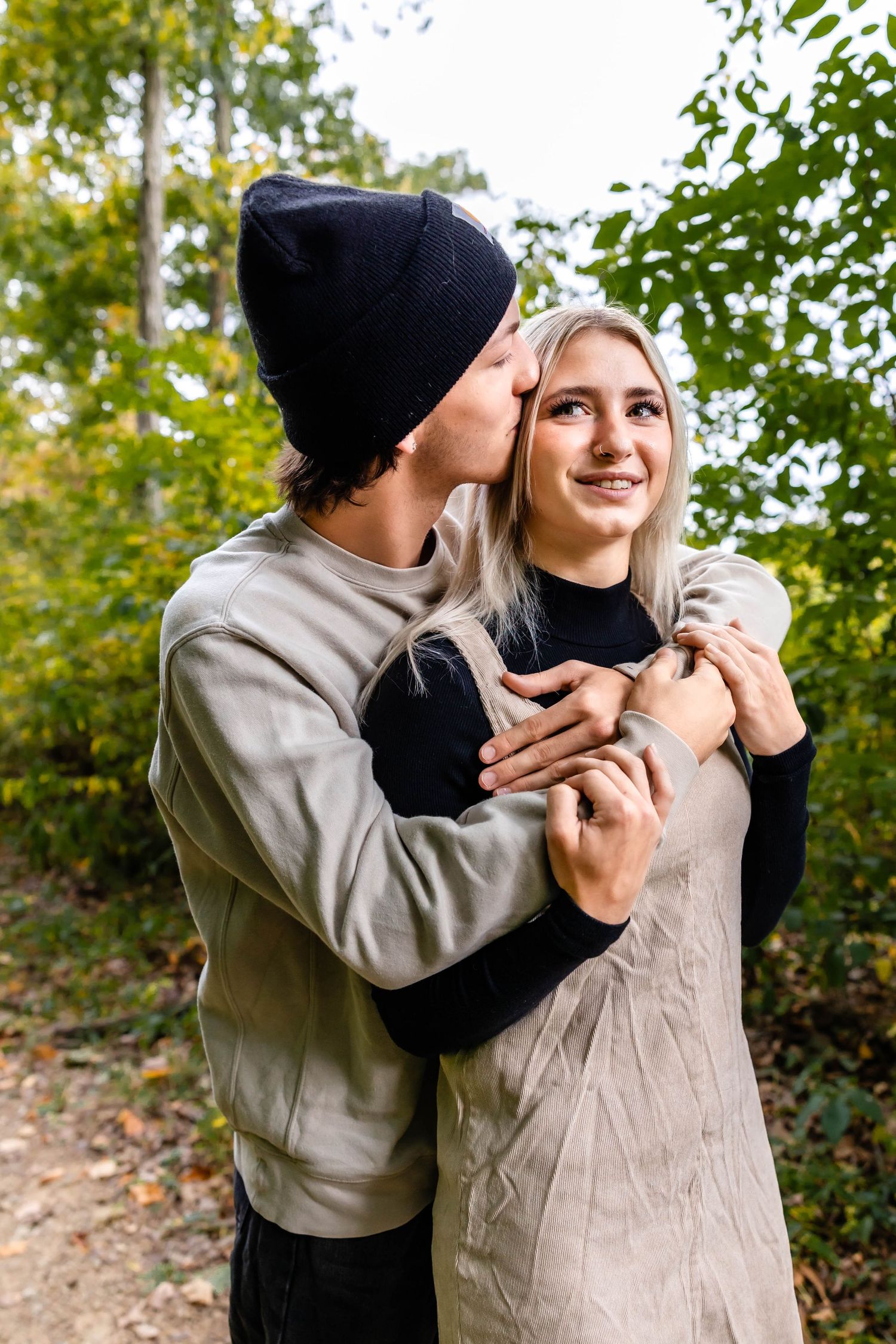 A romantic moment captured between a couple on an autumn forest path.