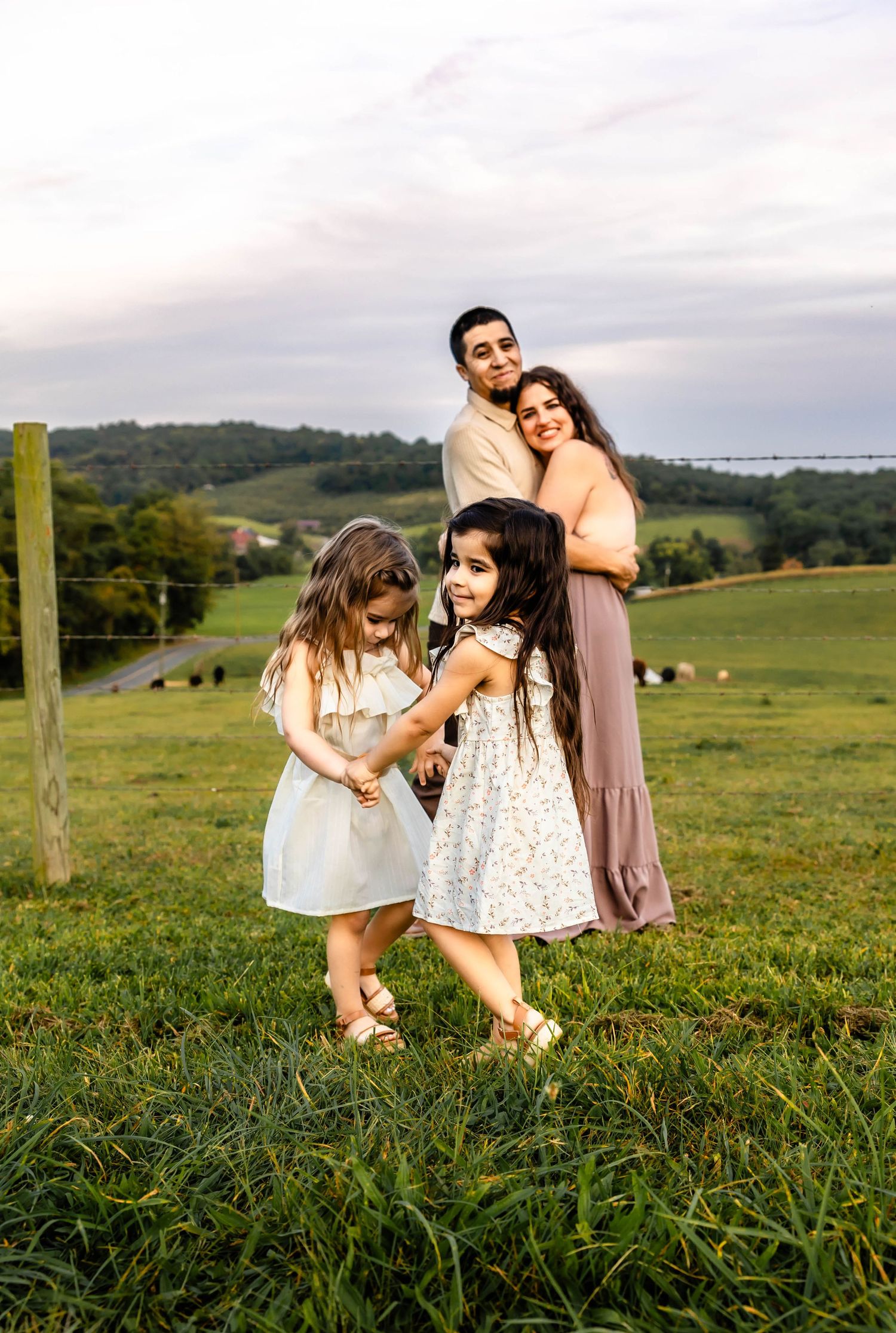A family poses for a cheerful portrait in front of rolling hills and farmland.