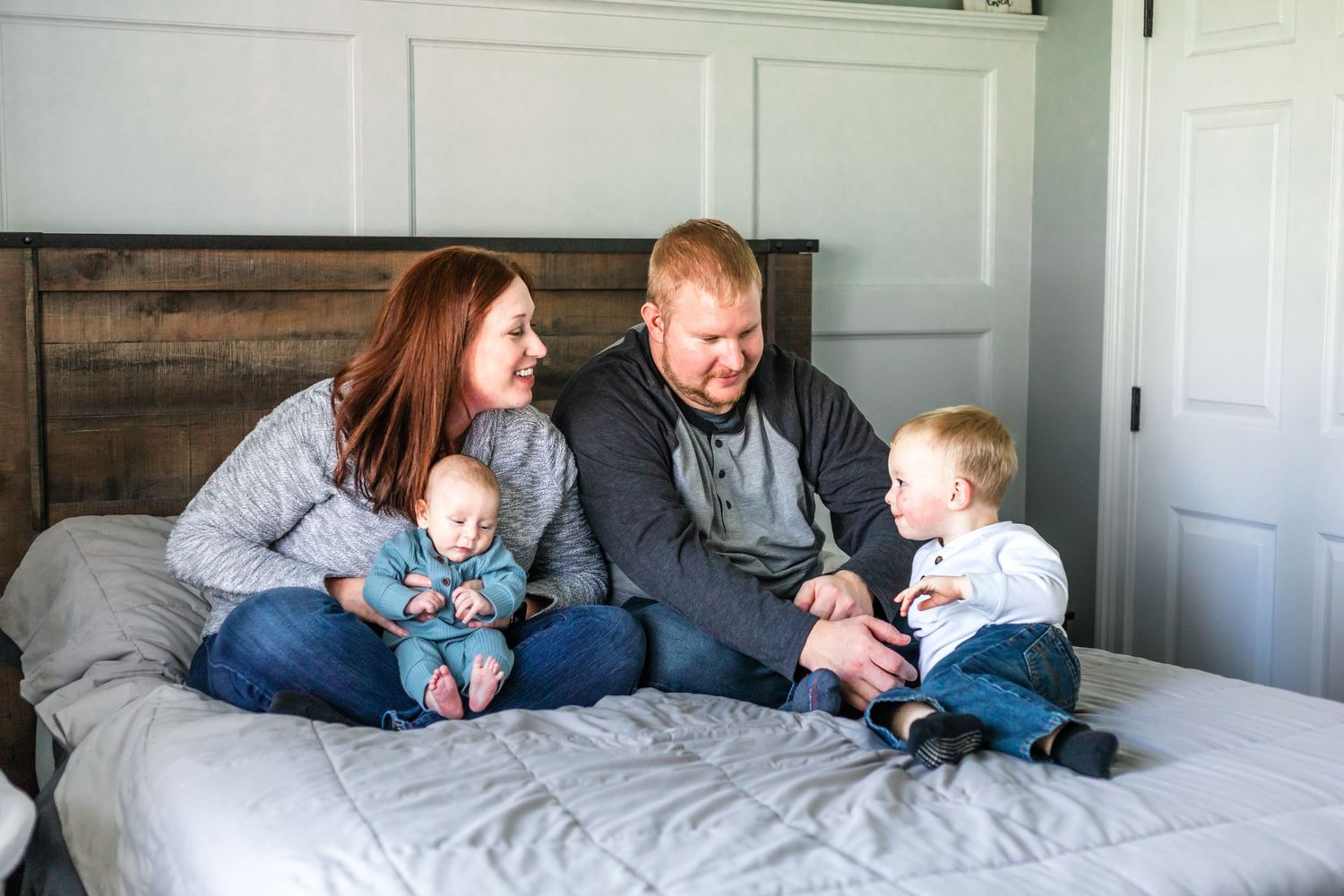 Joyful family moment captured on bed with everyone laughing together.