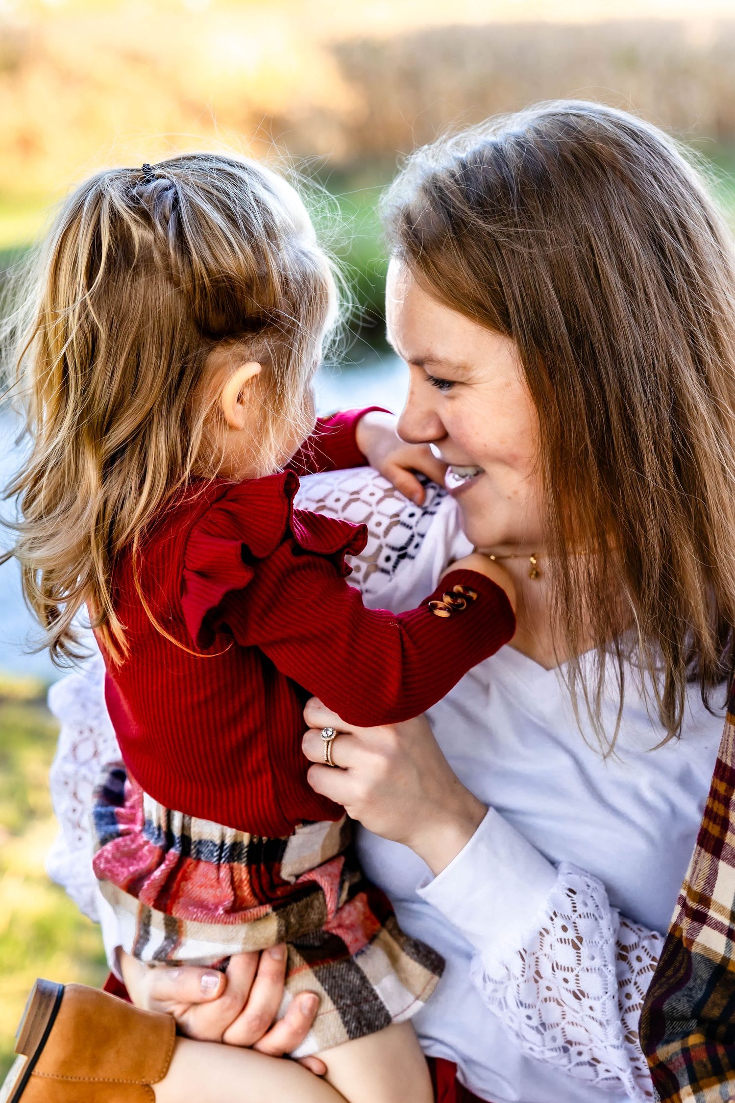 Sweet candid moment between mother and child in matching red outfits outdoors.