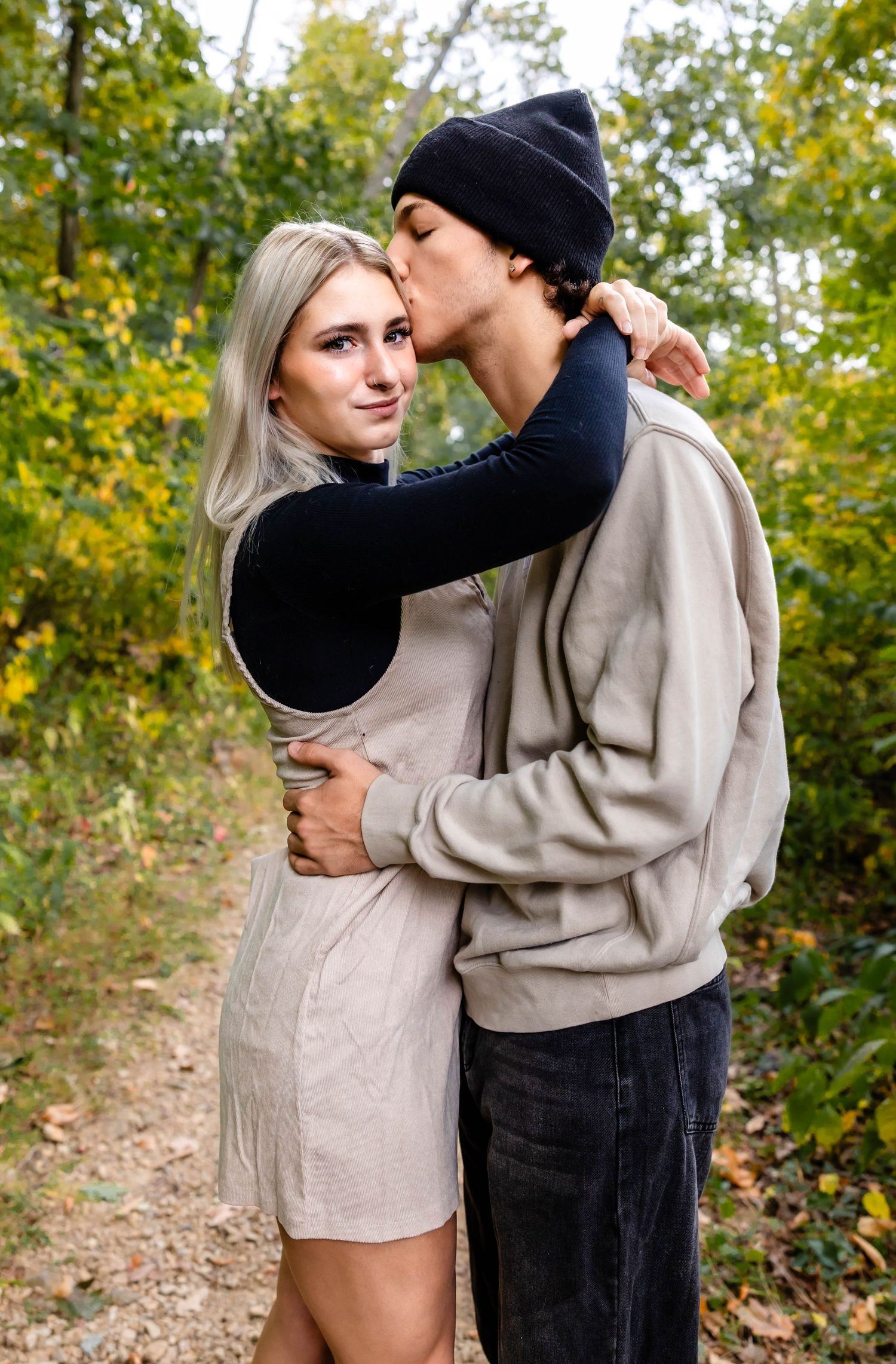 A sweet moment captured between a couple on an autumn path with golden leaves in background.