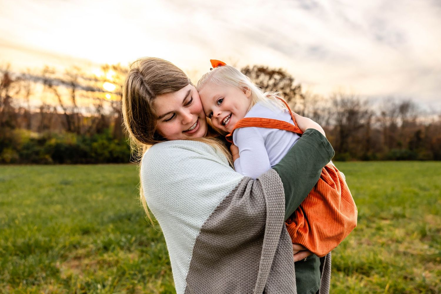 Sweet outdoor moment with parent and child hugging against autumn backdrop.