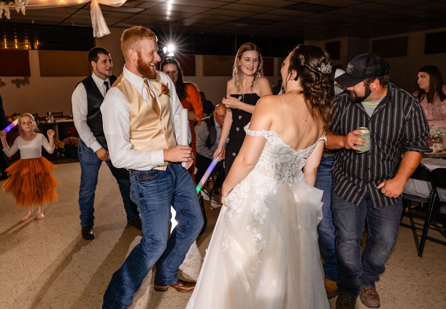 Wedding guests and newlyweds dance together at a casual reception celebration.