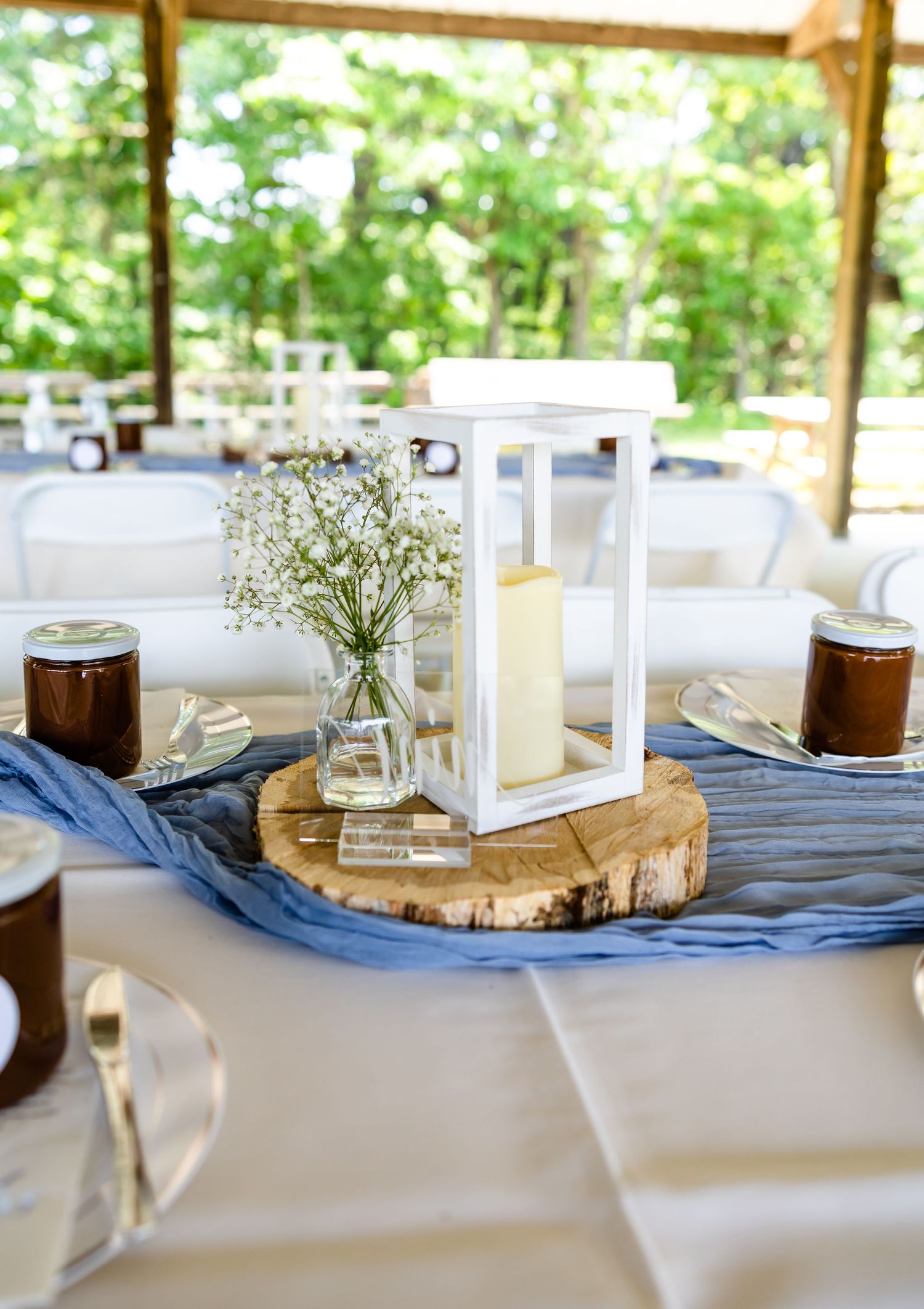 Rustic wedding table centerpiece with lantern, baby's breath and blue fabric on wood slice.