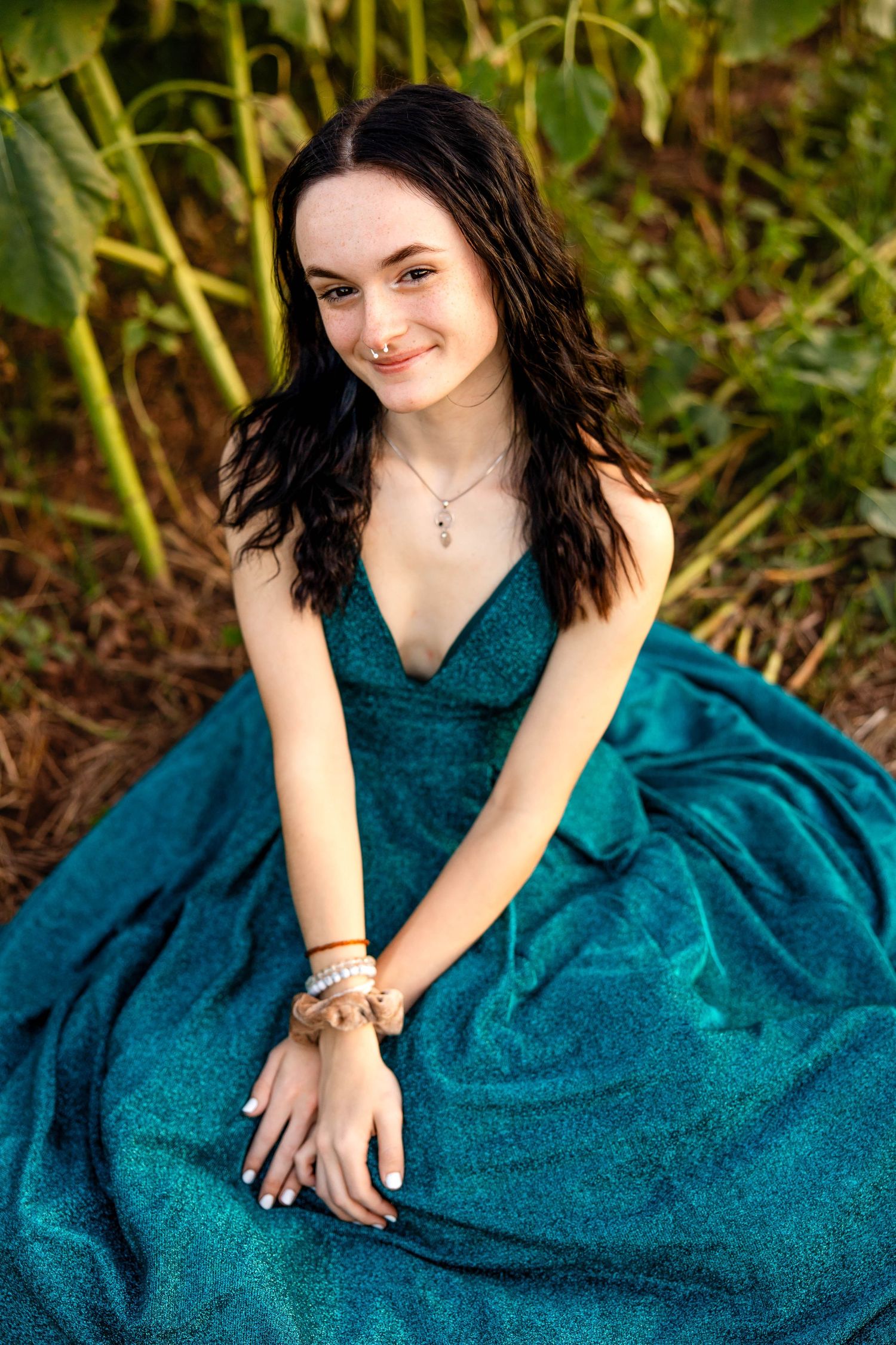 Portrait in teal formal dress sitting amidst garden greenery.