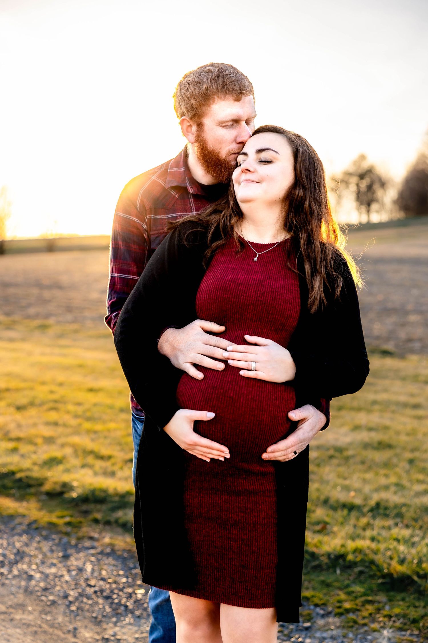 Intimate maternity photoshoot with couple embracing in warm sunset light.